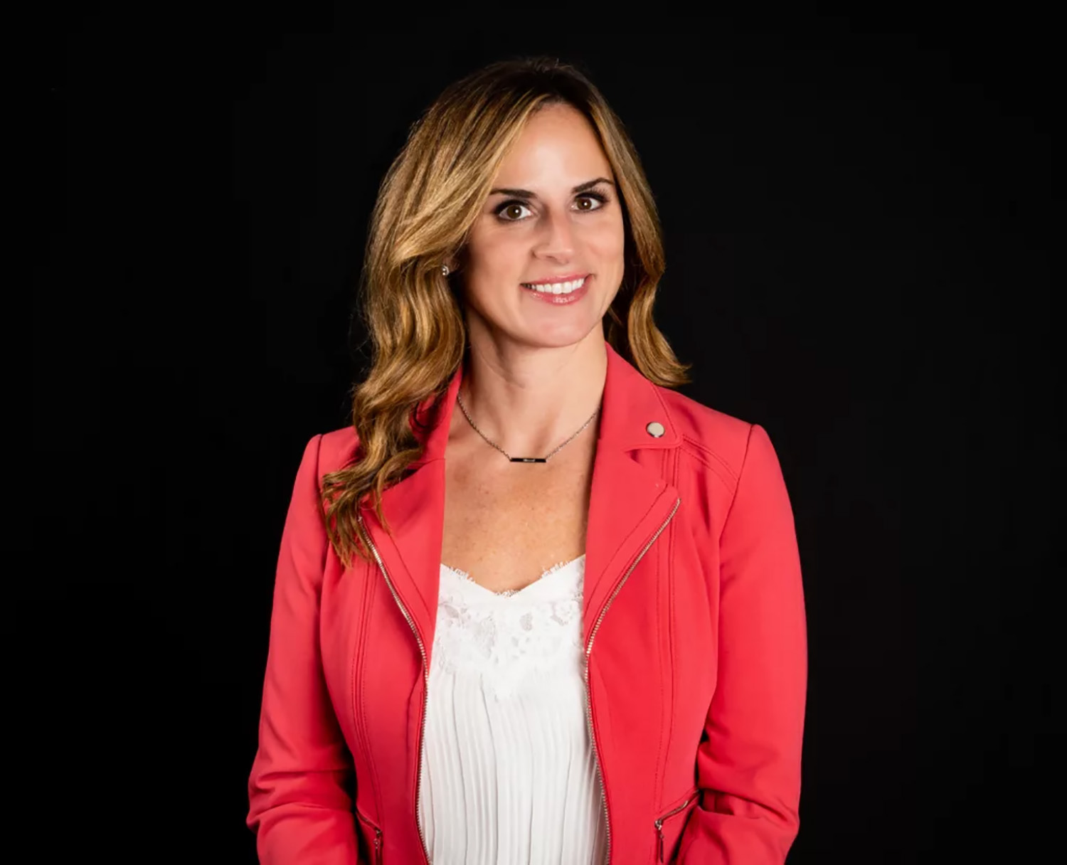 A photo of Dr. Zona wearing a red jacket in front of a black background