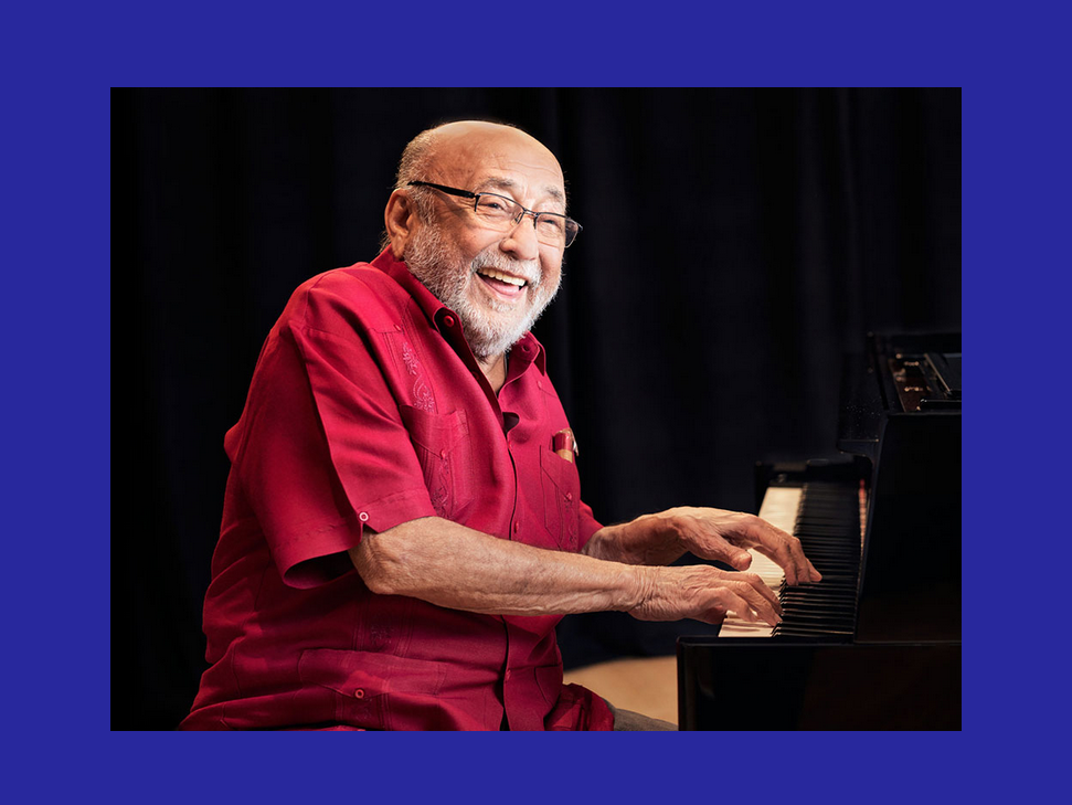 Eddie Palmieri smiling and playing the piano