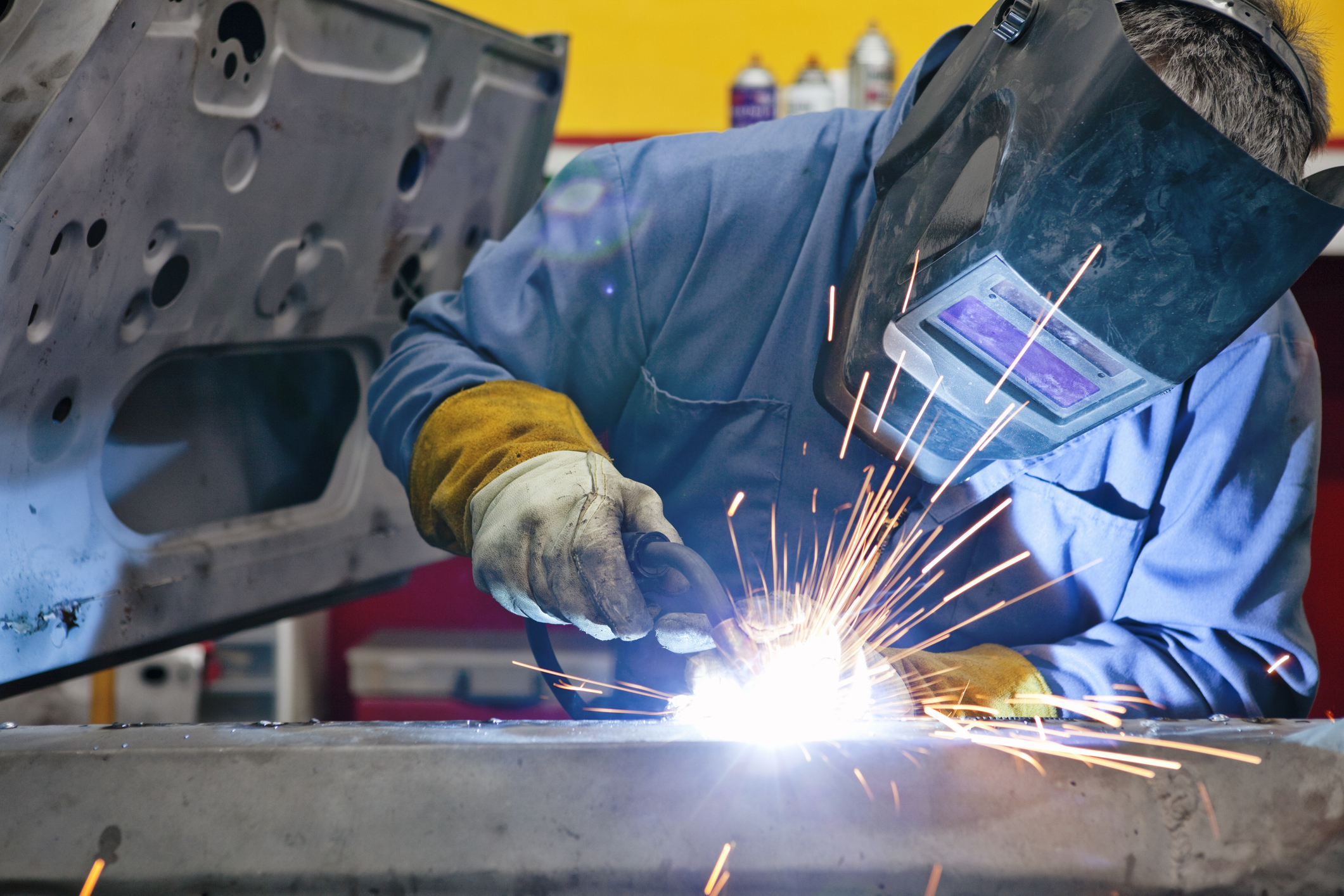 A welder uses a torch on a car