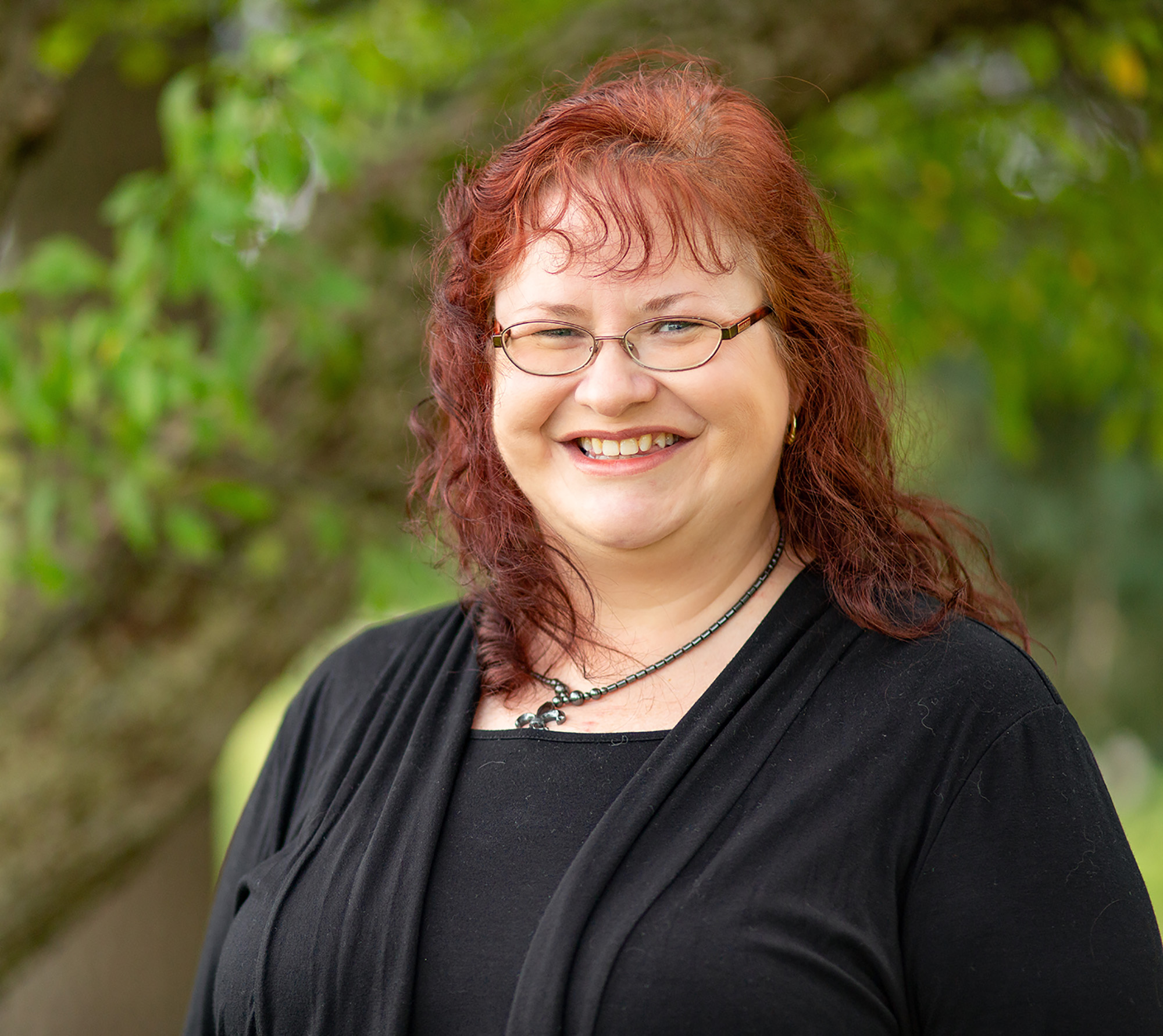 A photo of Gill taken outside. She is smiling and wearing a black jacket.