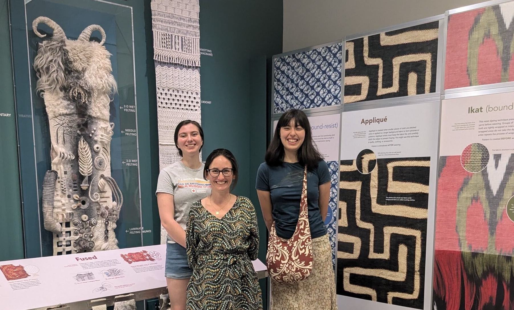 Three women in front of textile museum exhibition