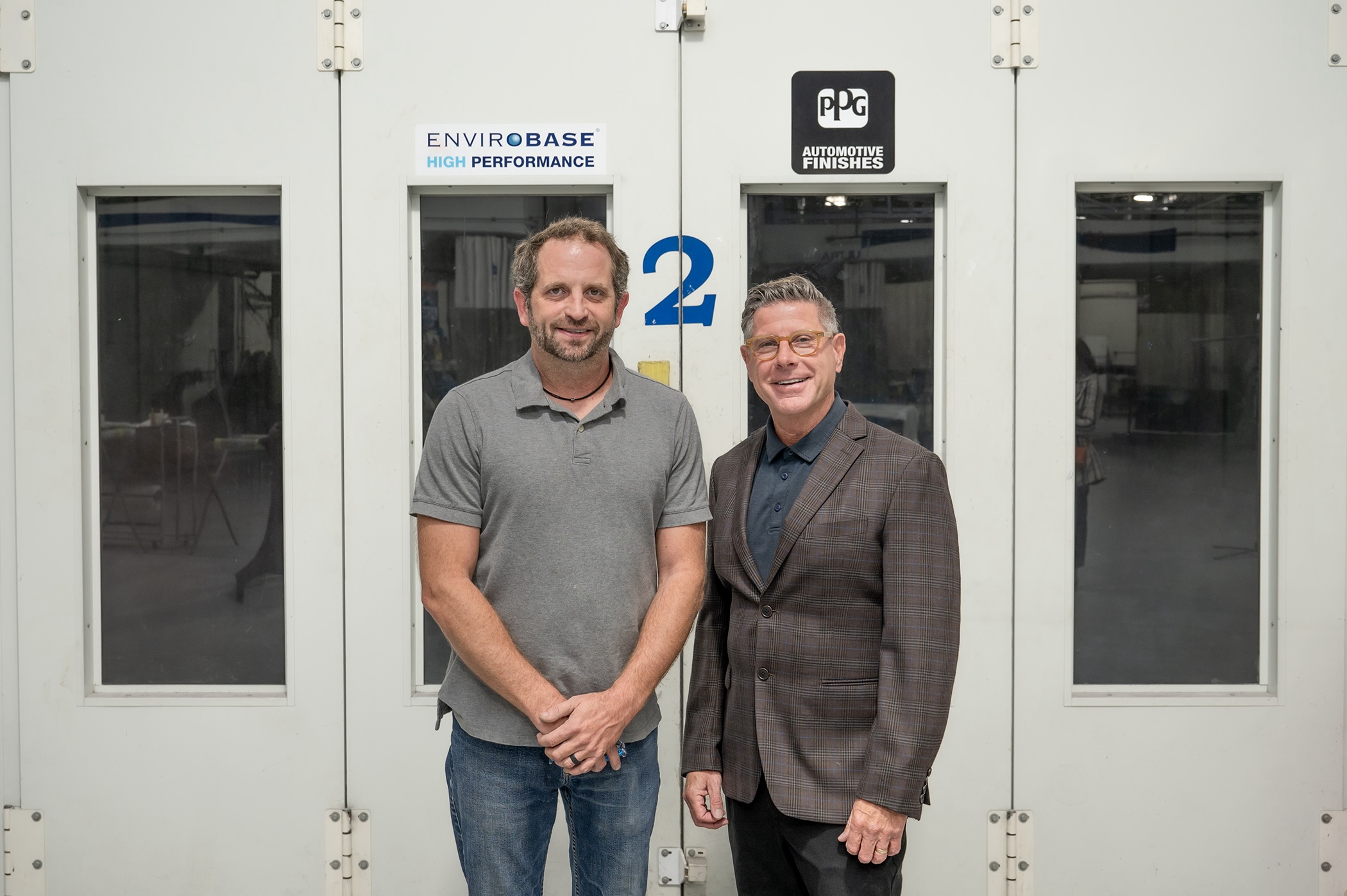 Shaun D. Hack, instructor and co-department head of collision repair at Pennsylvania College of Technology, and Todd Warren, territory manager for PPG Industries, stand in Penn College's collision repair lab