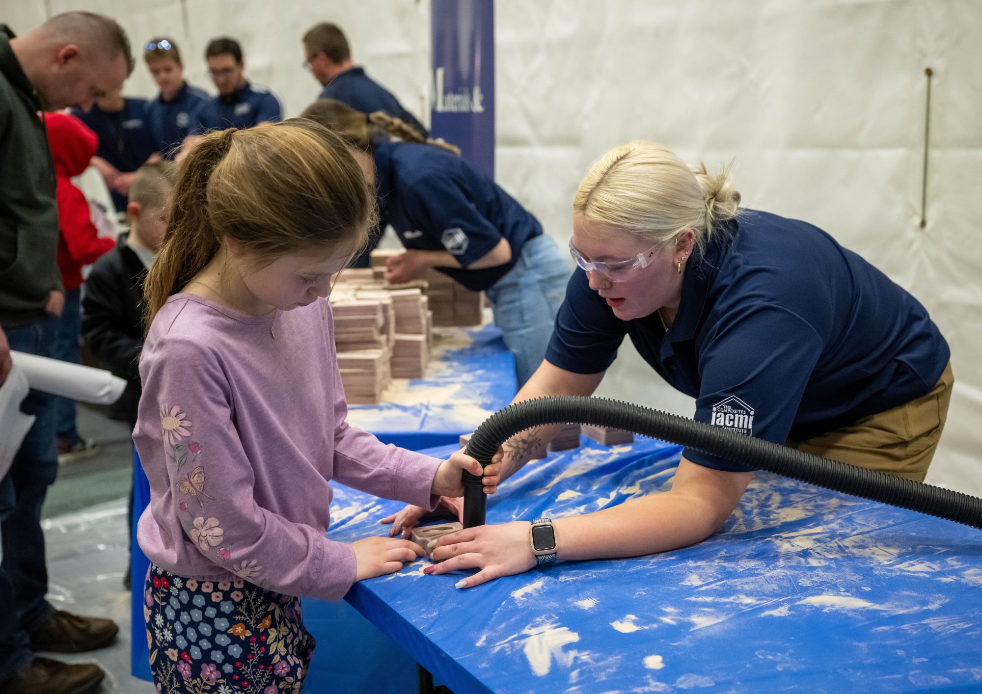 A volunteer helps a child clean out a sand mold used in metal-casting.