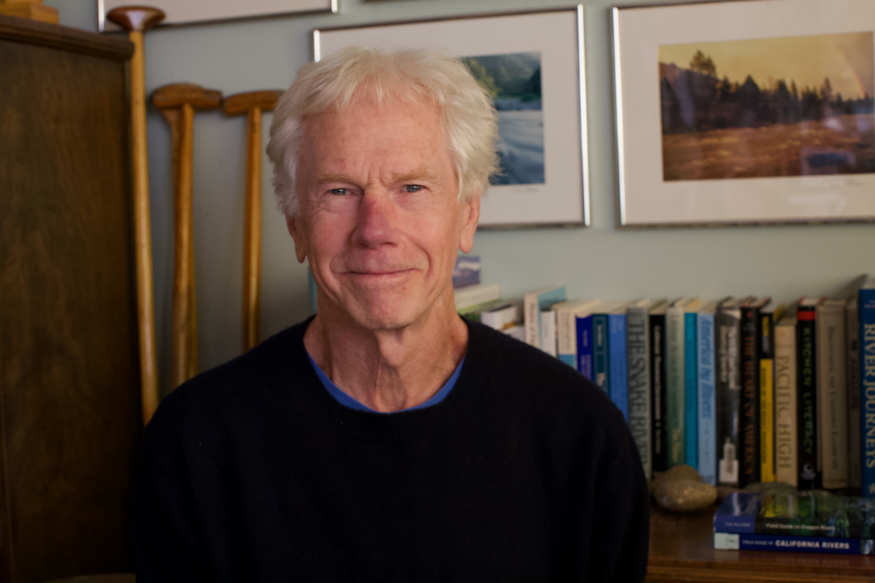 A man smiling in front of a bookshelf.