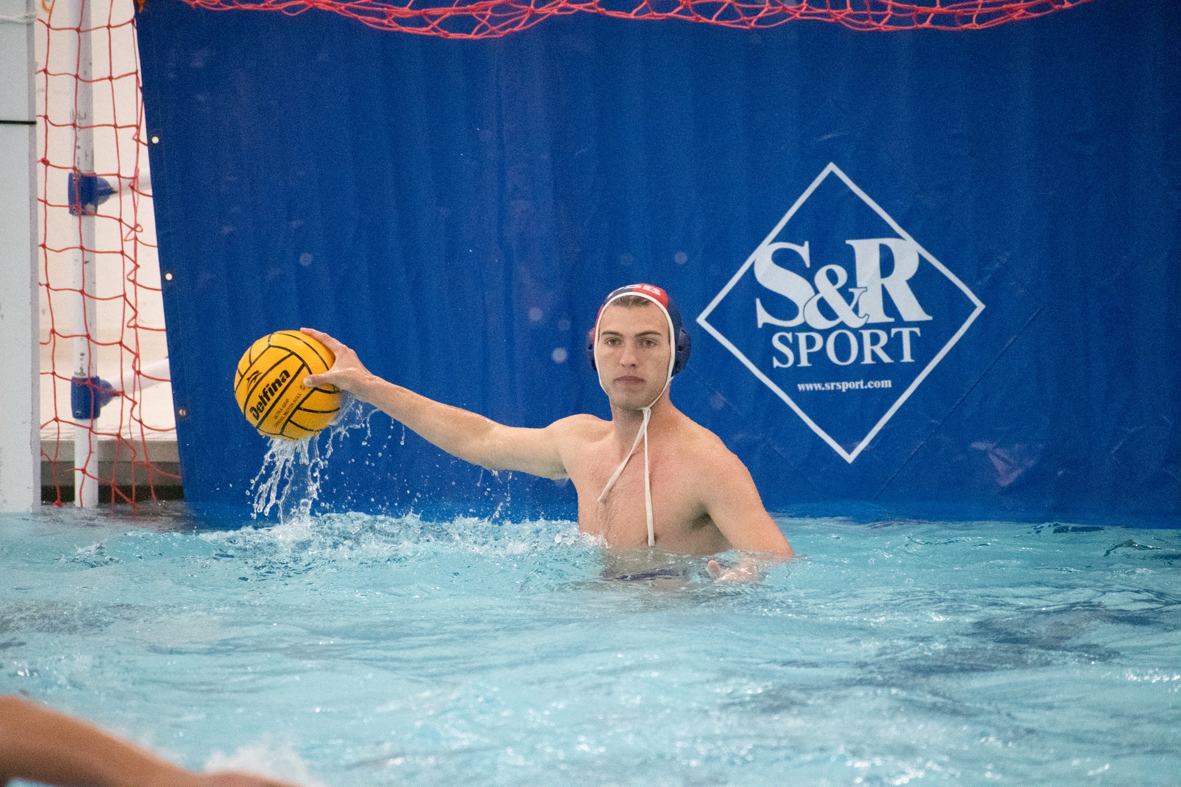 A goalkeeper for the Penn State Behrend men's water polo team prepares to throw the ball.