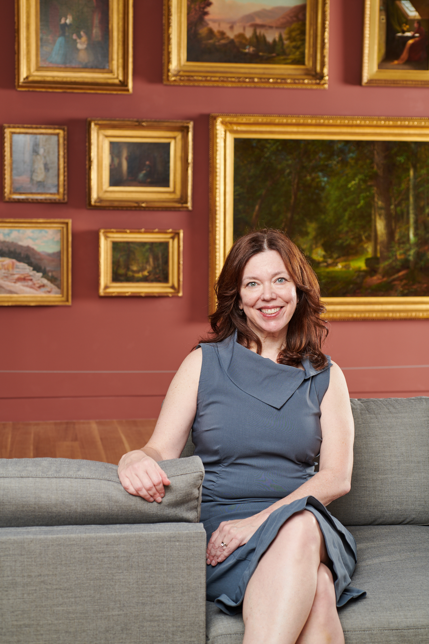 Woman with dark hair sitting on couch in front of a gallery wall