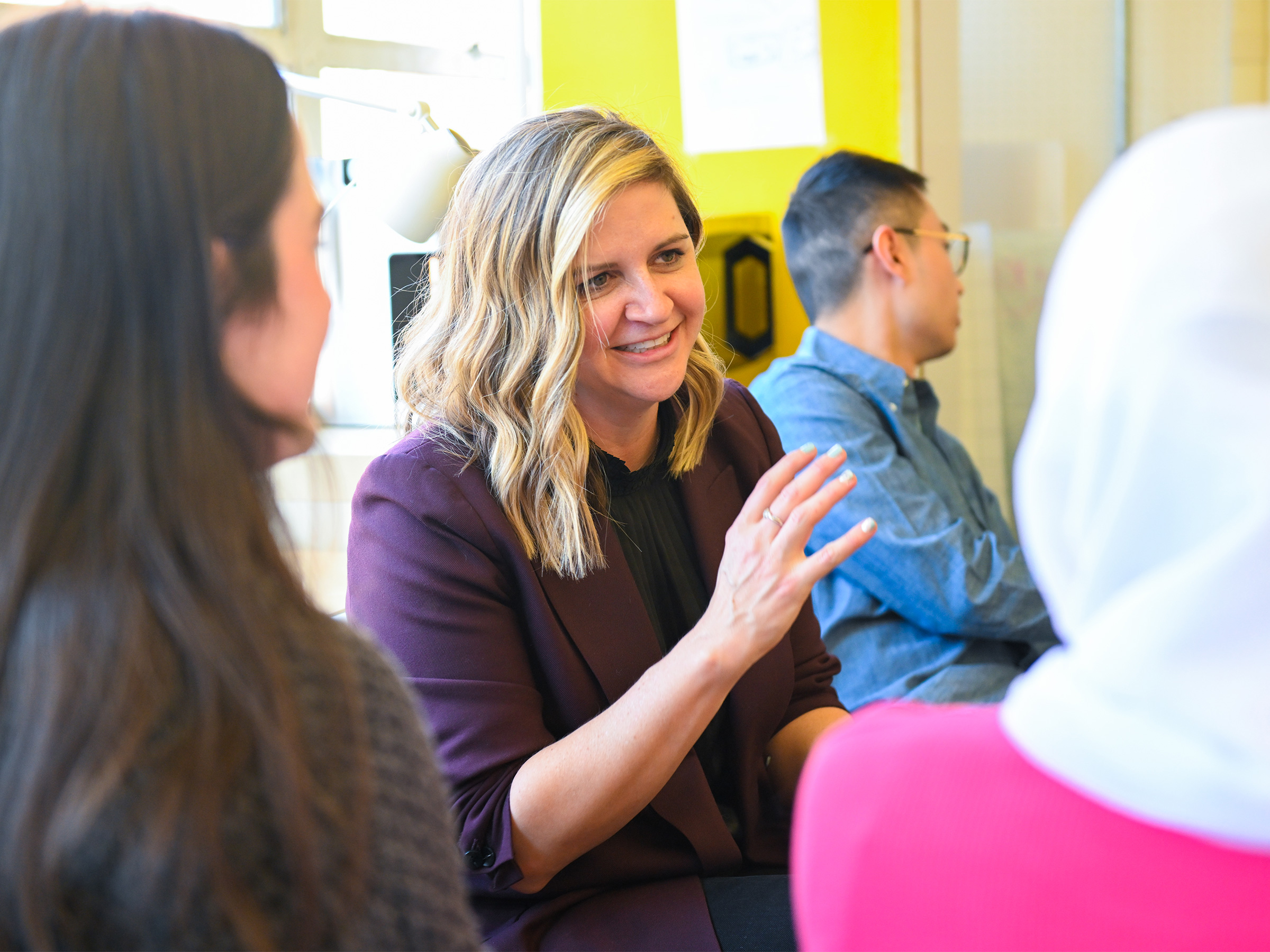 An individual smiles and converses in a group of people. 