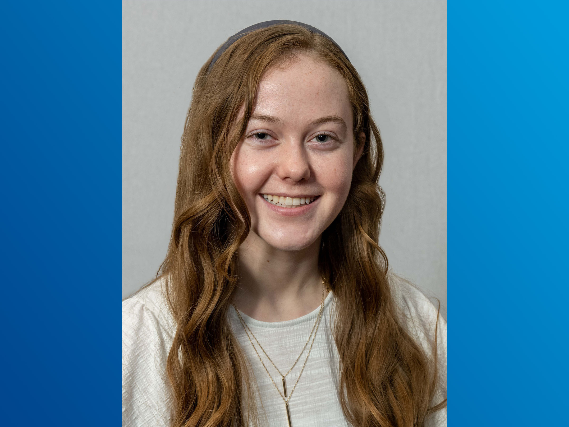 A headshot of an individual on a blue background. 