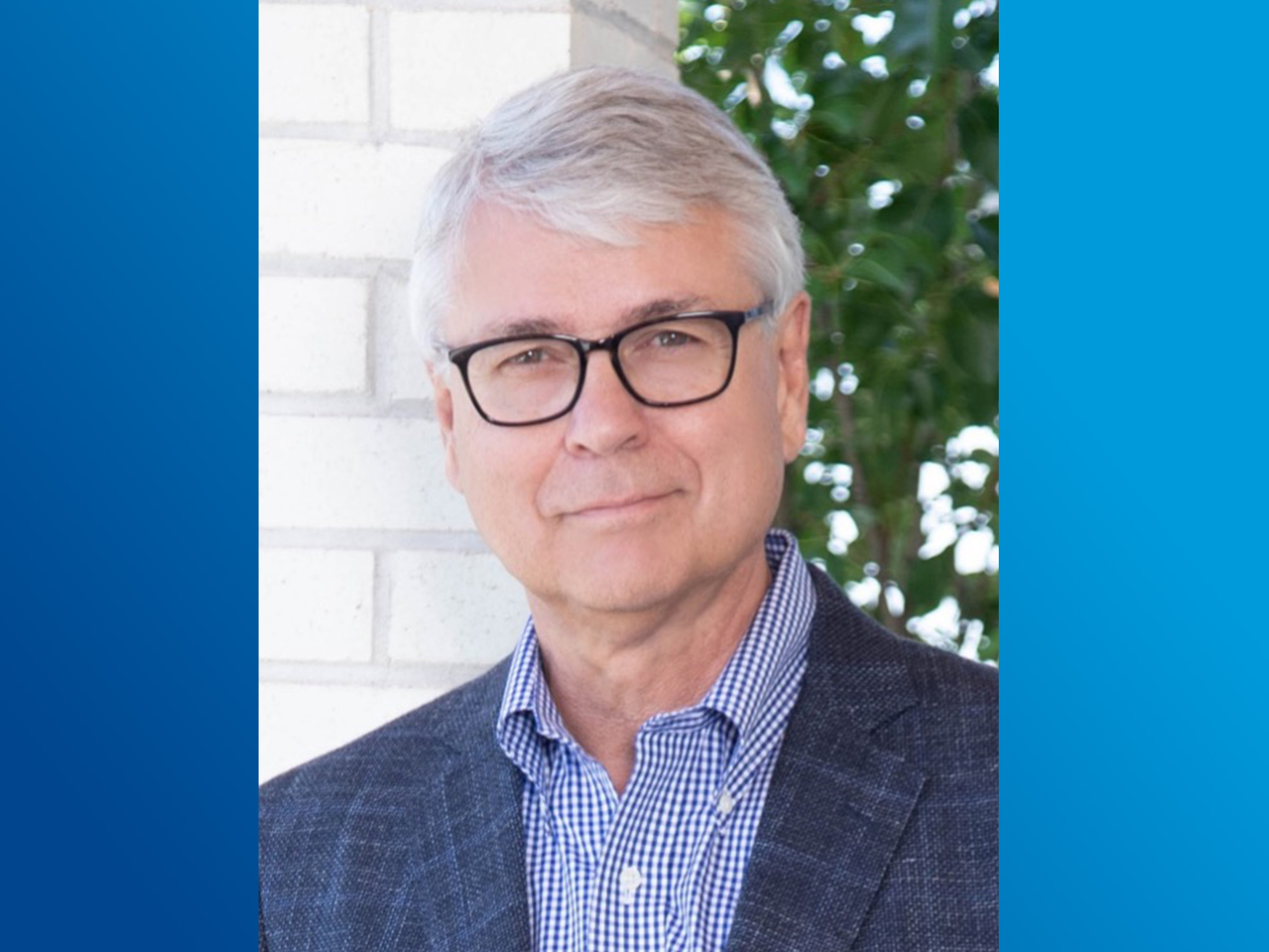 A headshot of an individual on a blue background. 