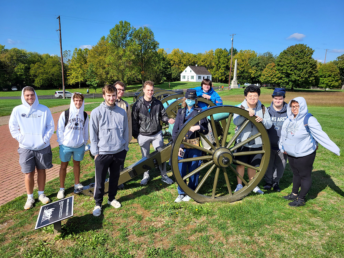 Penn State Altoona history students pose for a photo around a cannon at the Antietam battleground site