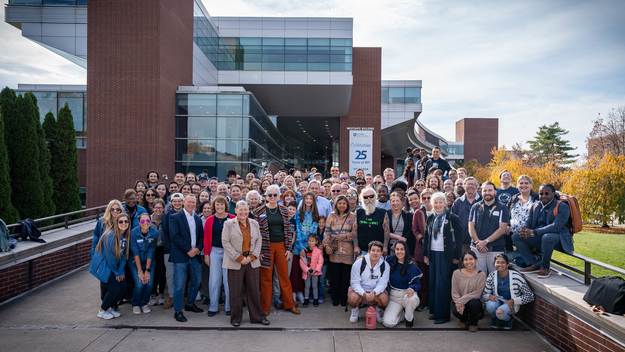 large group of people gather in front of campus building