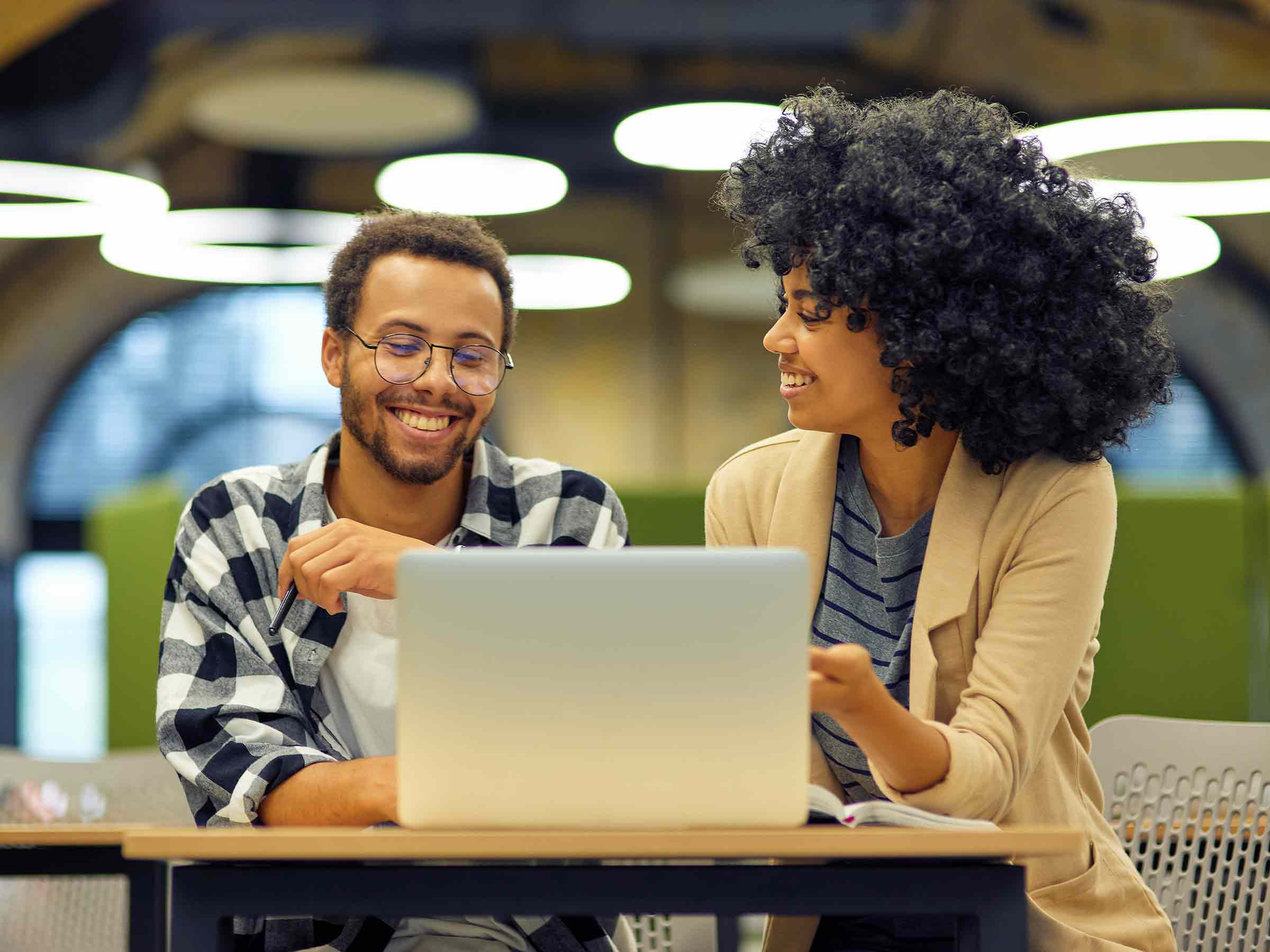 smiling man and woman working together with a laptop