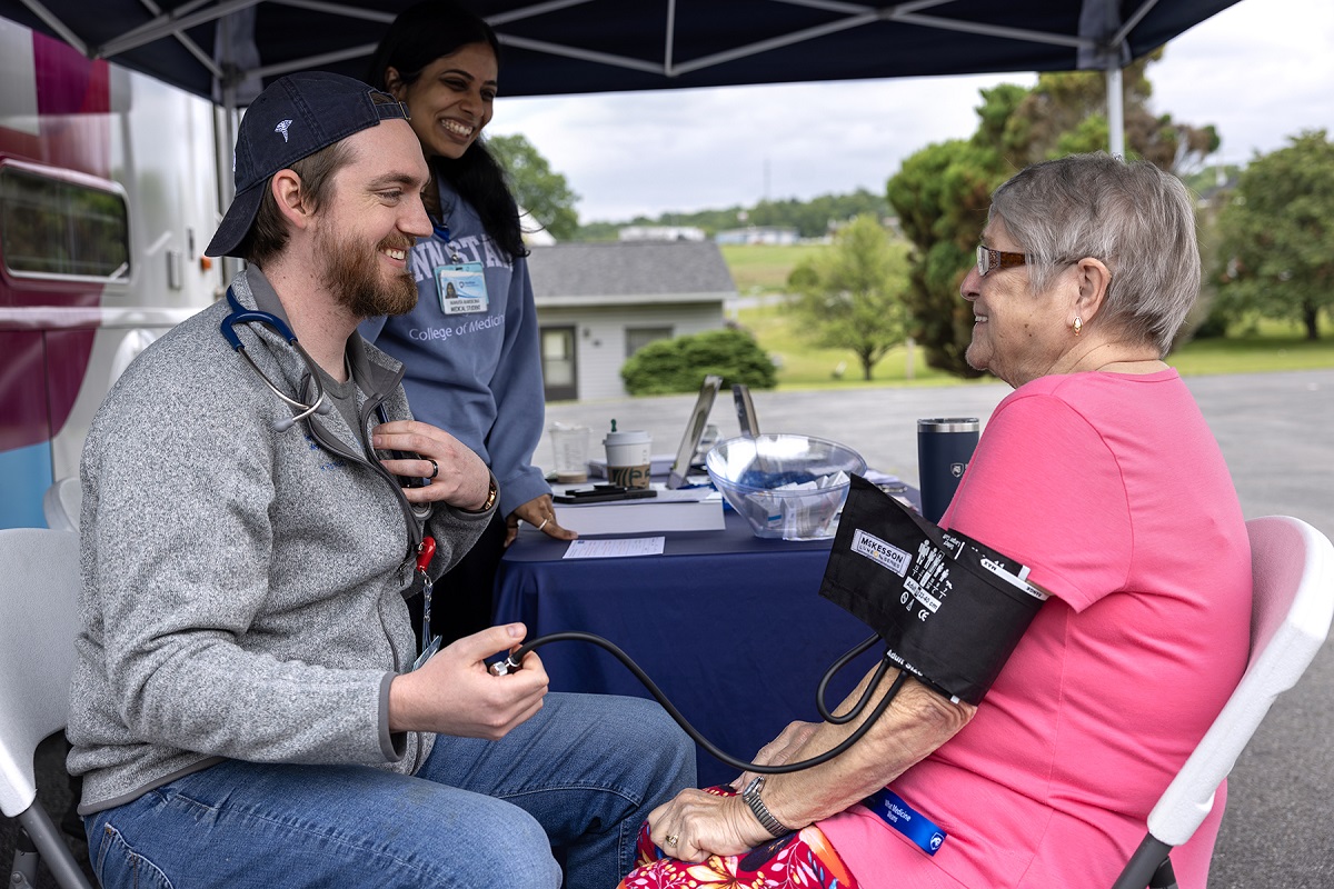 A medical student gives a woman a blood pressure screening.