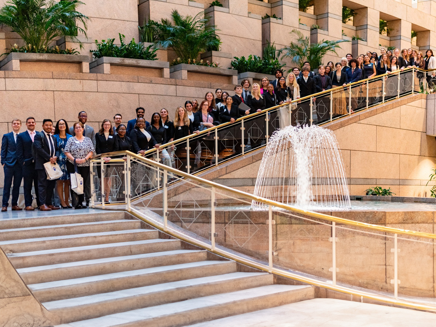 Liberal Arts students, alumni and staff stand on stairs behind a fountain at the City Club of Washington on Sept. 24 during a professional development and networking event.