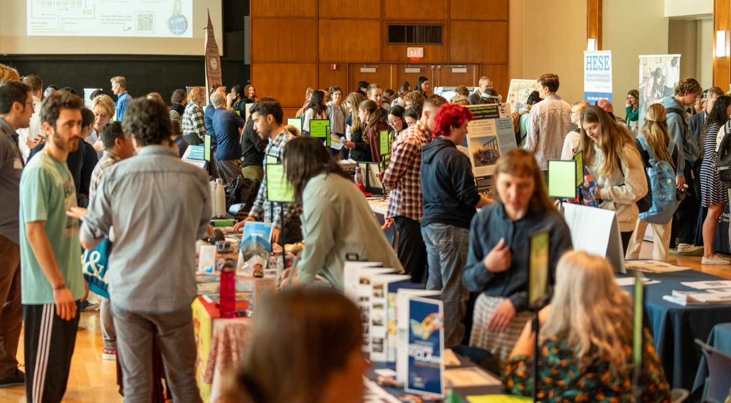 A bustling fair with dozens of students at various tables