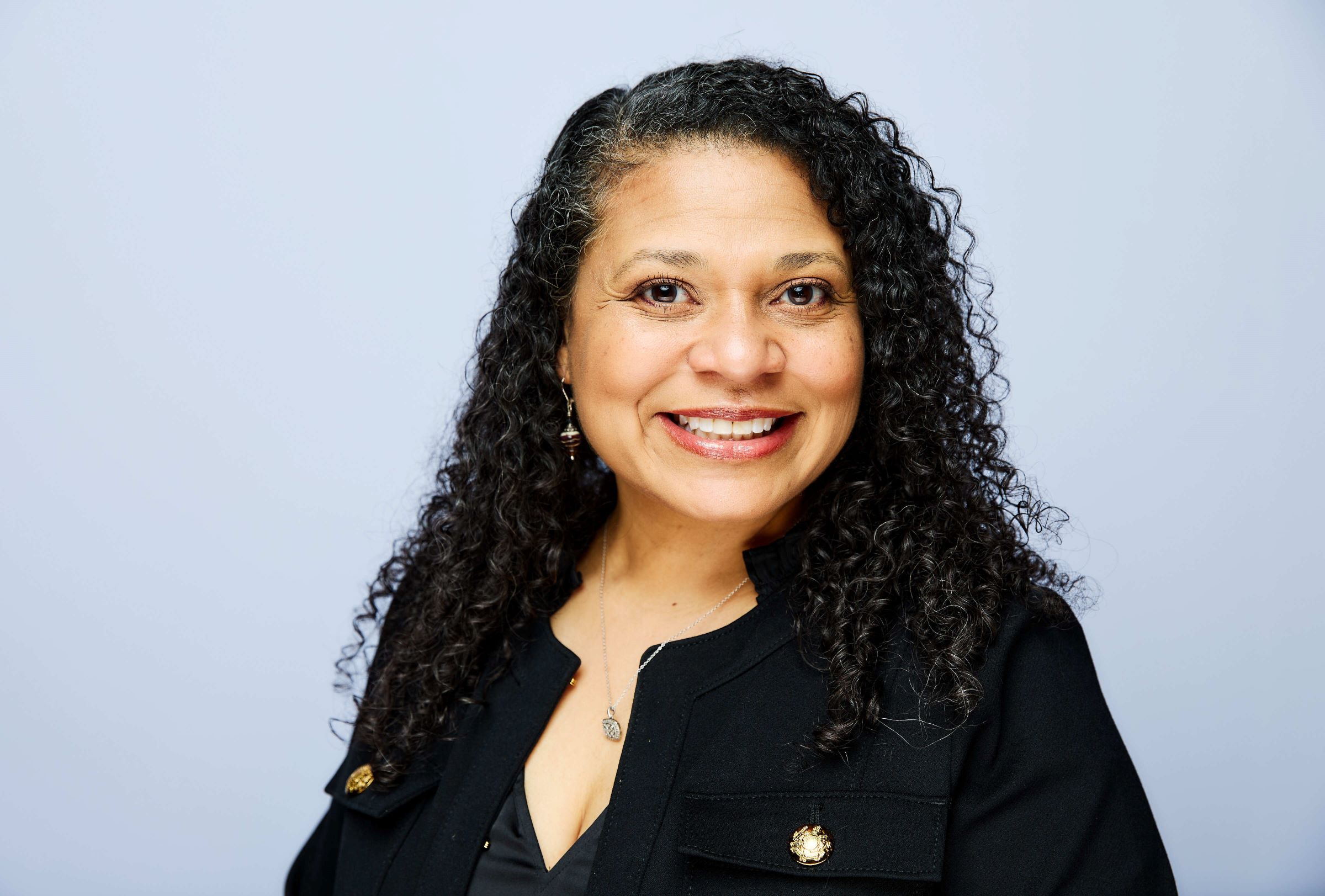 headshot of person with gray curly hair in business attire