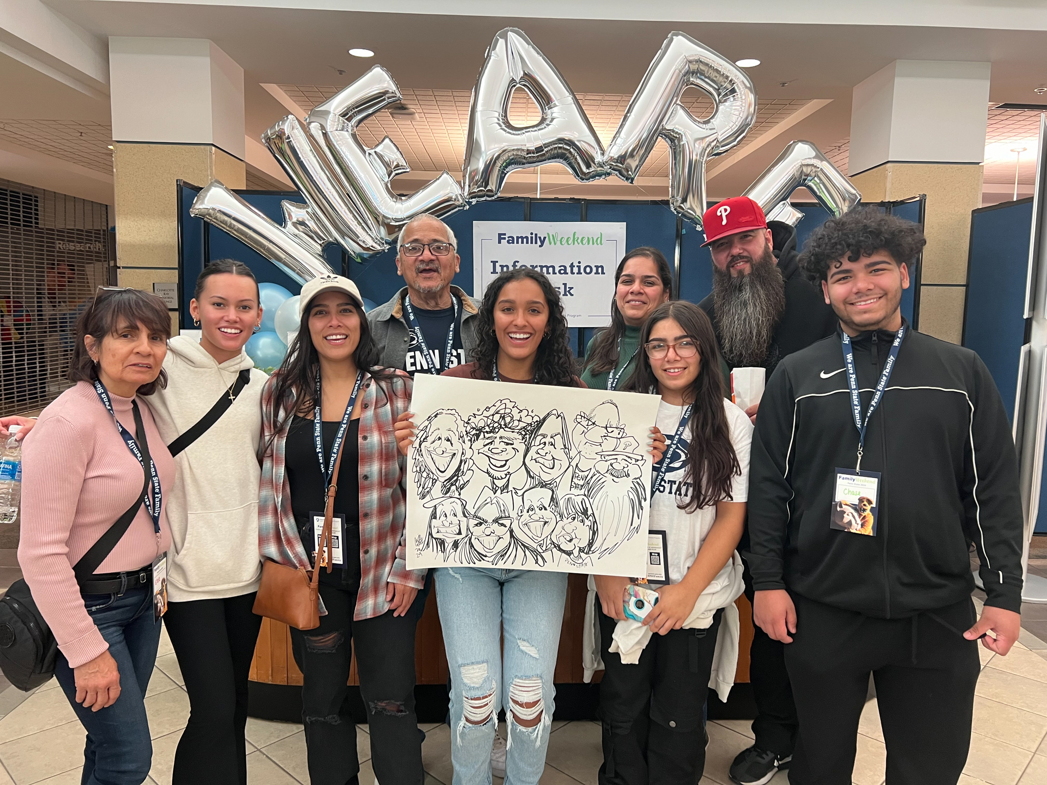 A family smiles with their student under some We Are balloons