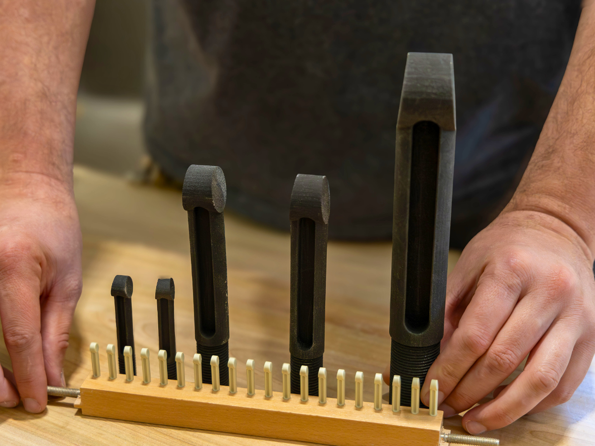 The 3D-printed pegs (back) compared in size to the average-sized loom pegs (front).