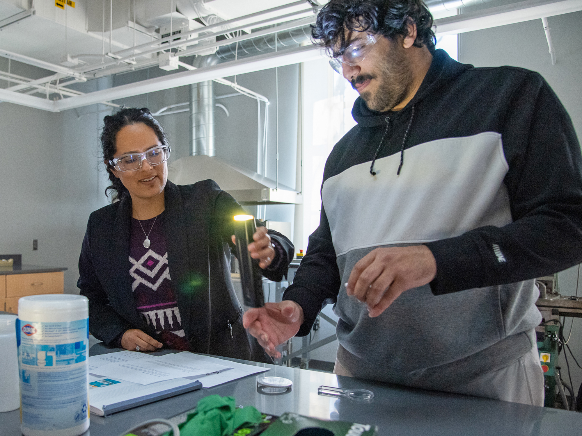 A lab instructor teaches an undergraduate student how to work safely in the lab.