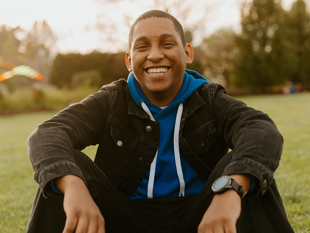 Smiling seated man in coat and hoodie