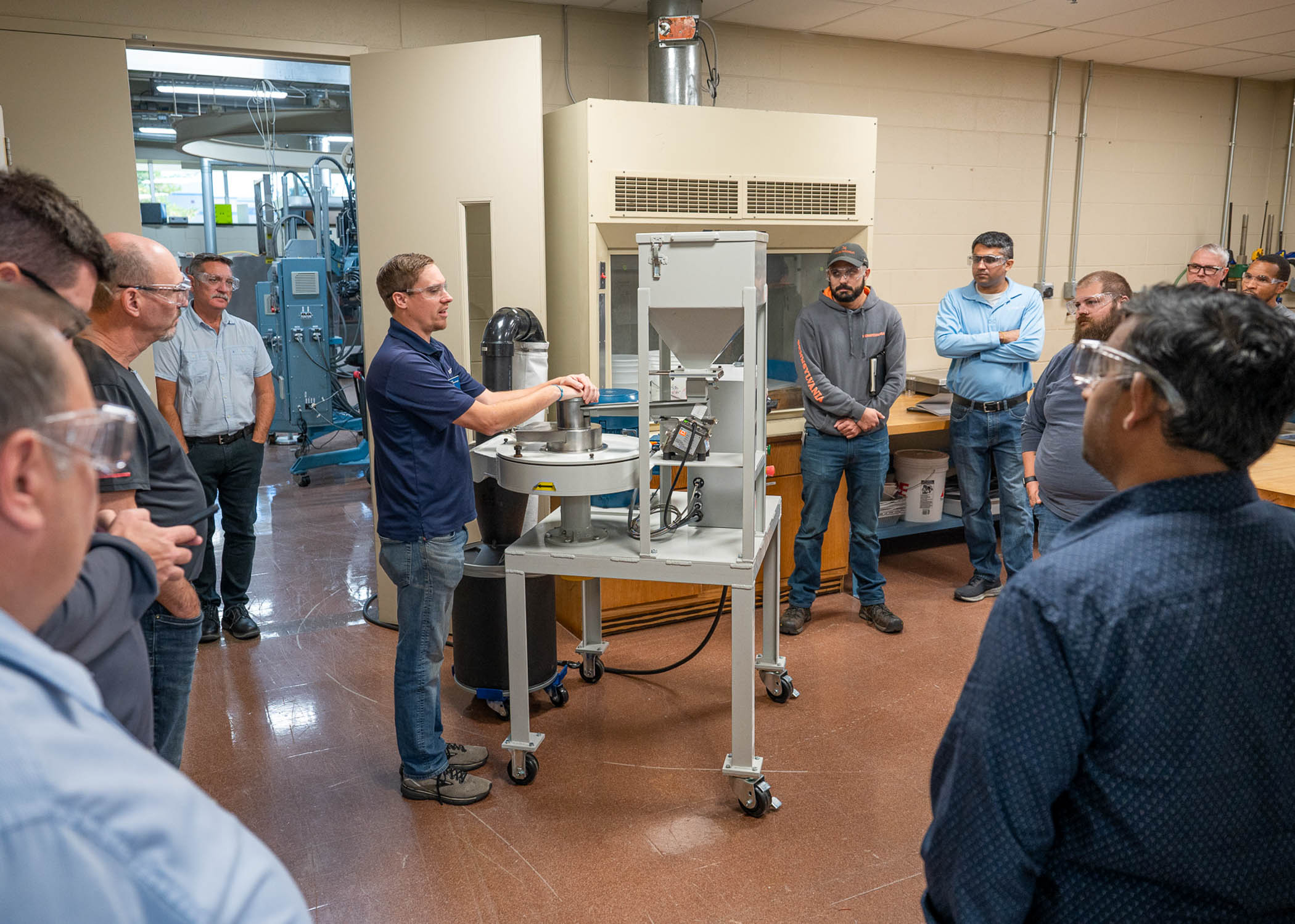 A group of people gather round a demonstration in a workshop.