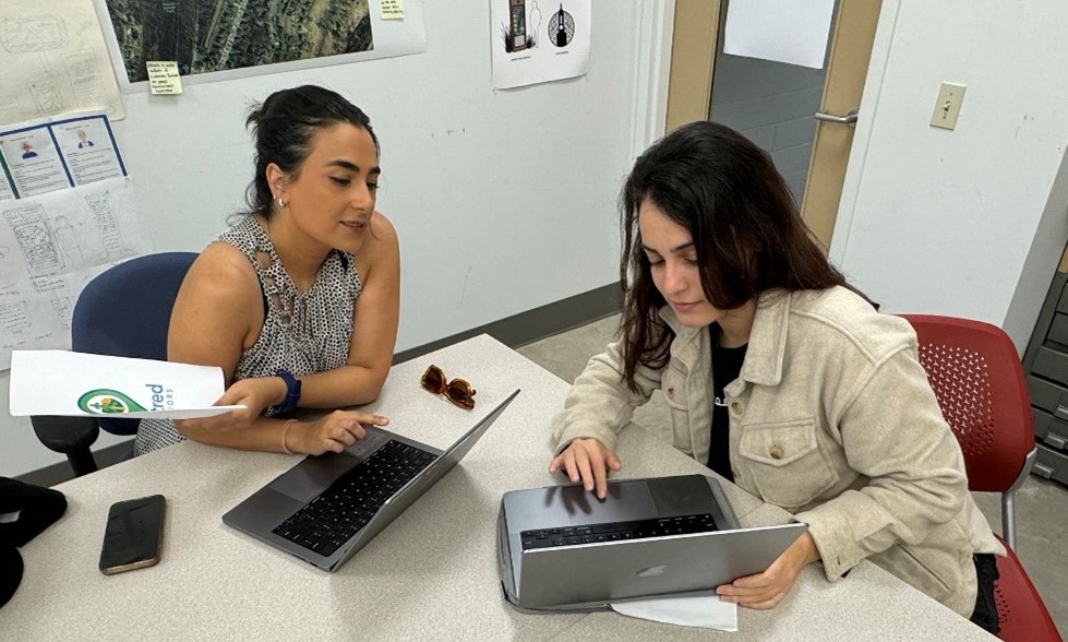 Two people work on a laptop together.