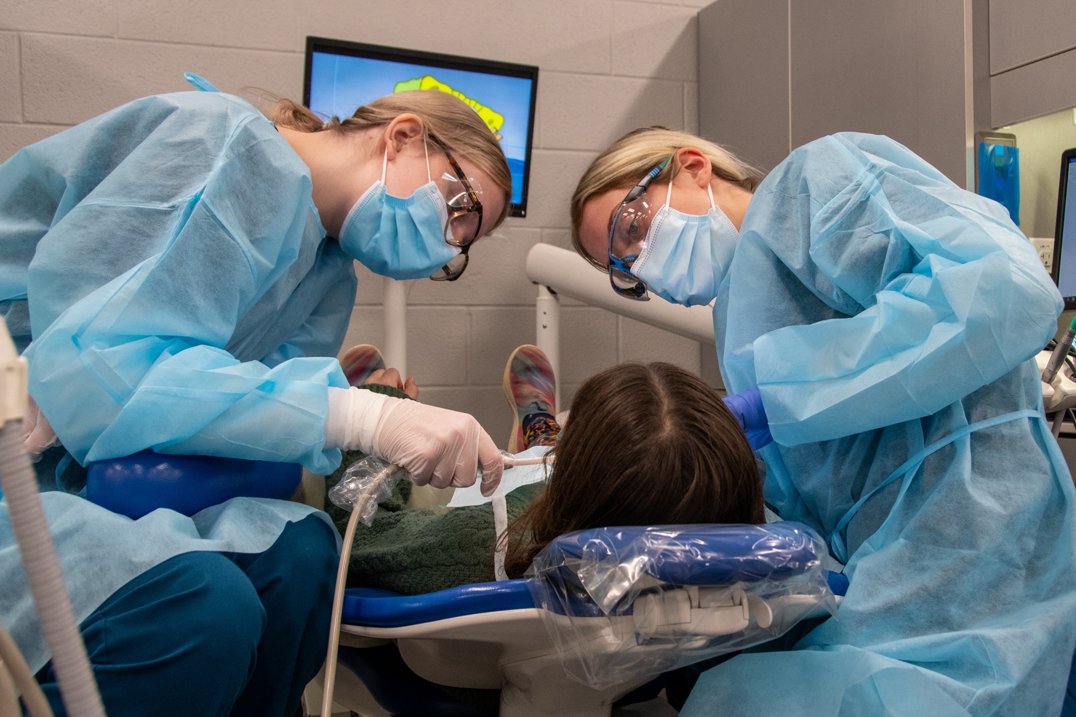 Two Penn College dental hygiene students examine a child's teeth during the 2023 Sealant Saturday event.