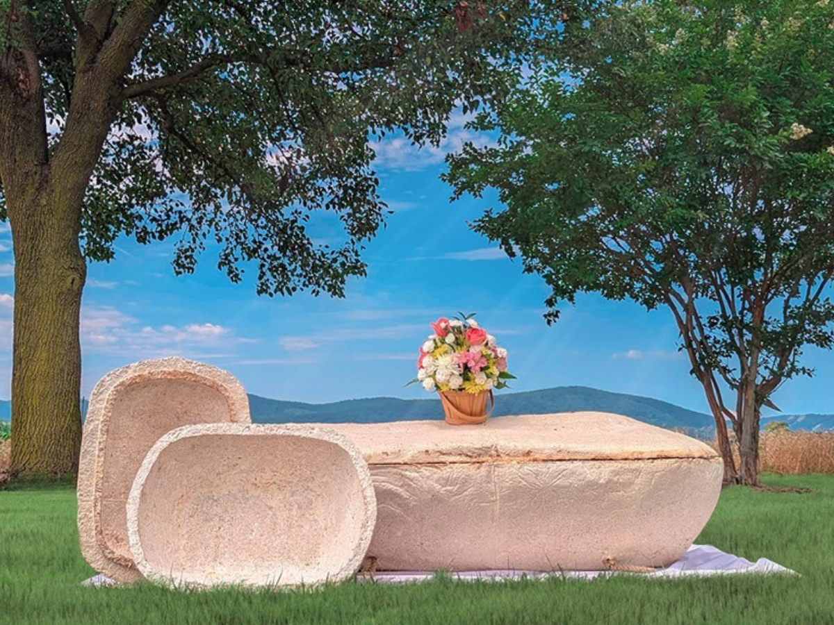 Both a human-sized coffin and a pet-sized coffin on display in a grassy outdoors scene