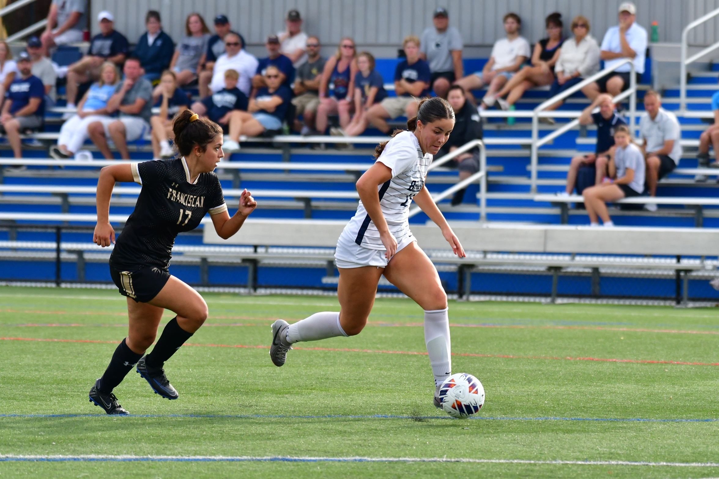 A Penn State Behrend soccer player advances the ball past a defender.