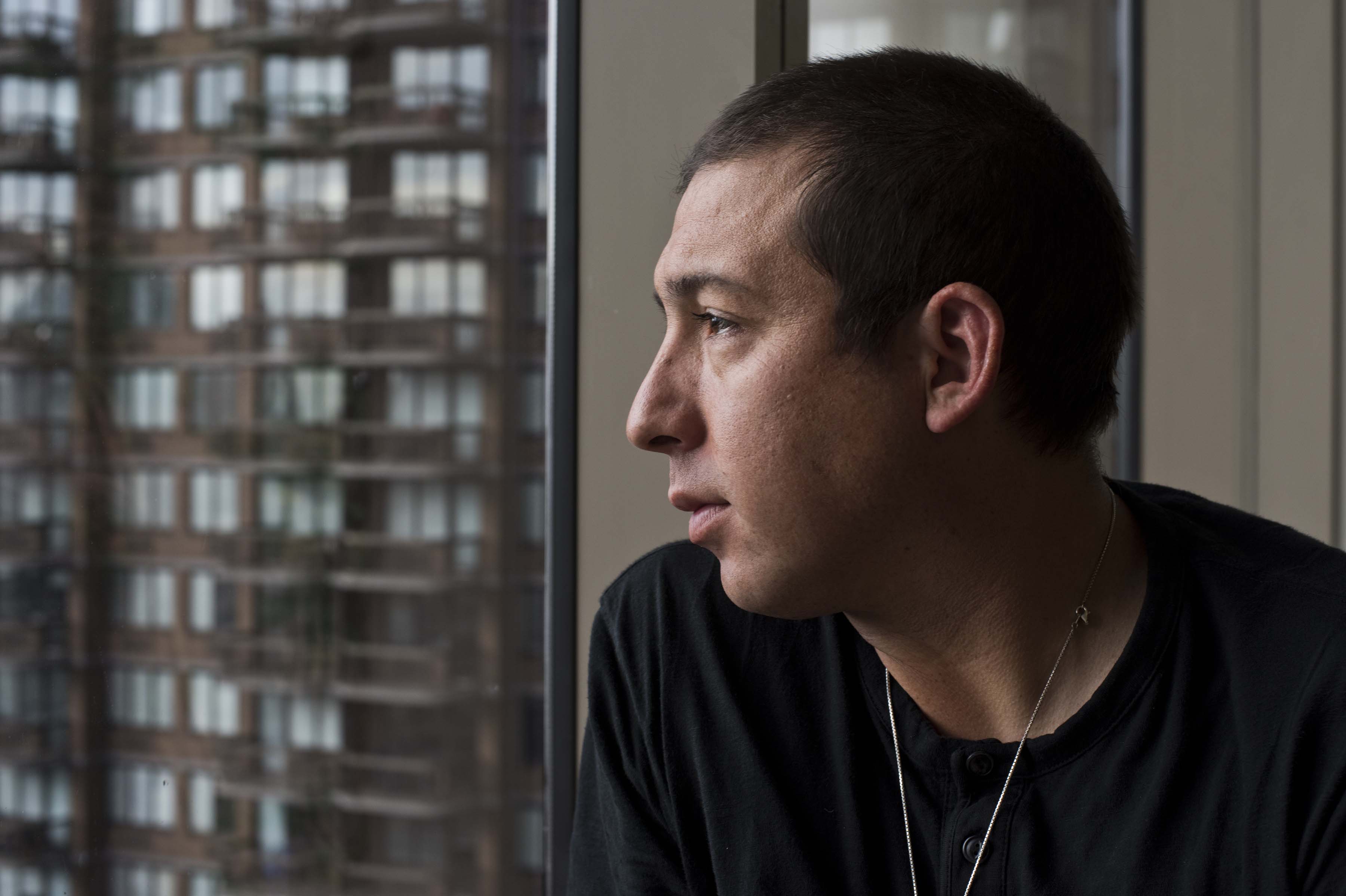 Profile photo of Tommy Orange staring out of a window.