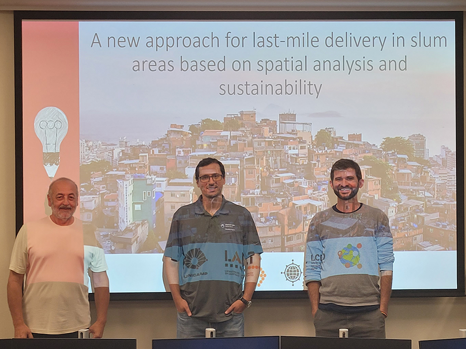 Three people standing against a presentation screen.