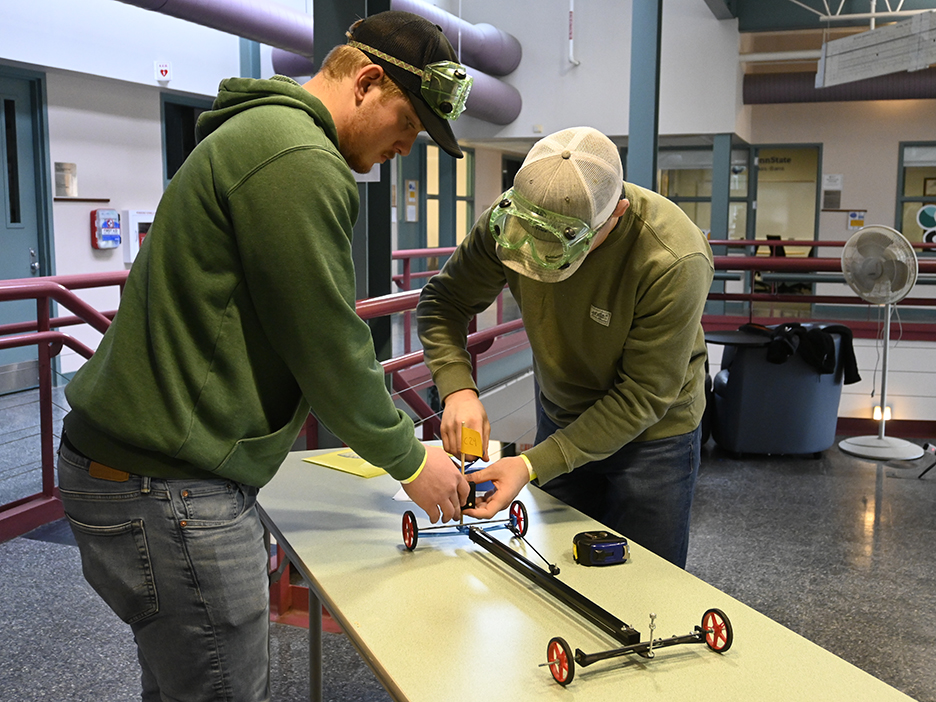 Two students work on a project on a table.