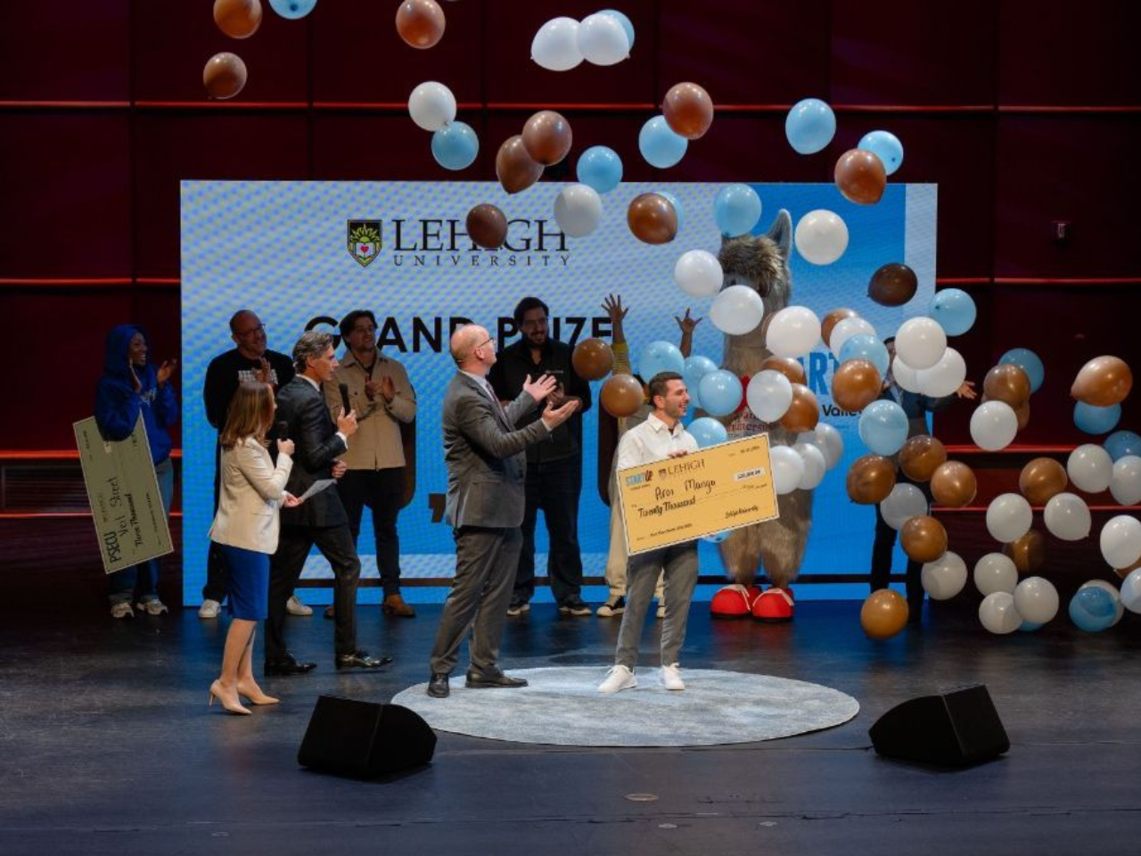 balloons fall from a stage ceiling over several people 