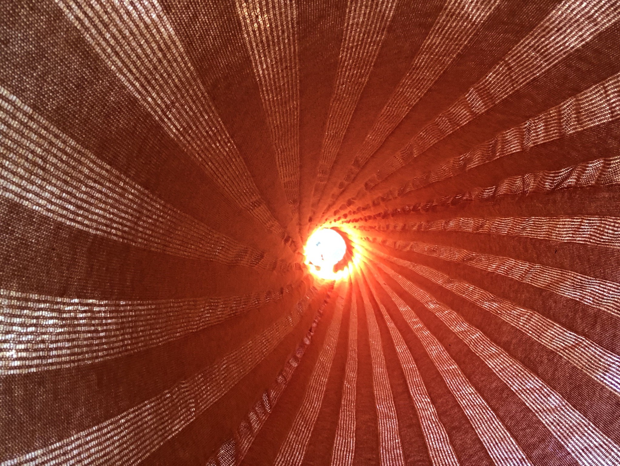 Abstract view of woven textiles in a spiral shape with red light at the center