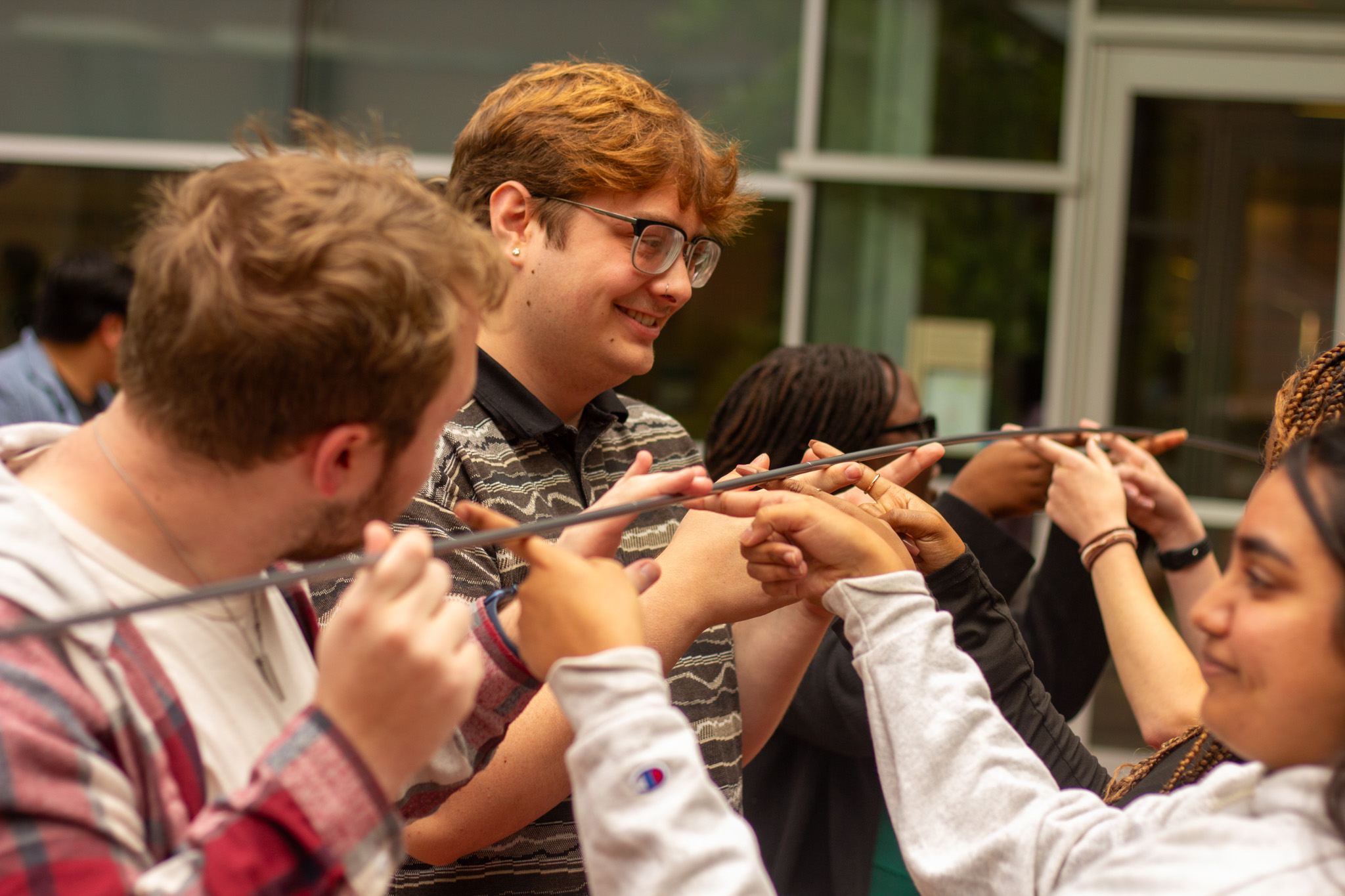 IDEA Ambassadors participate in a community building activity holding a bar in the air