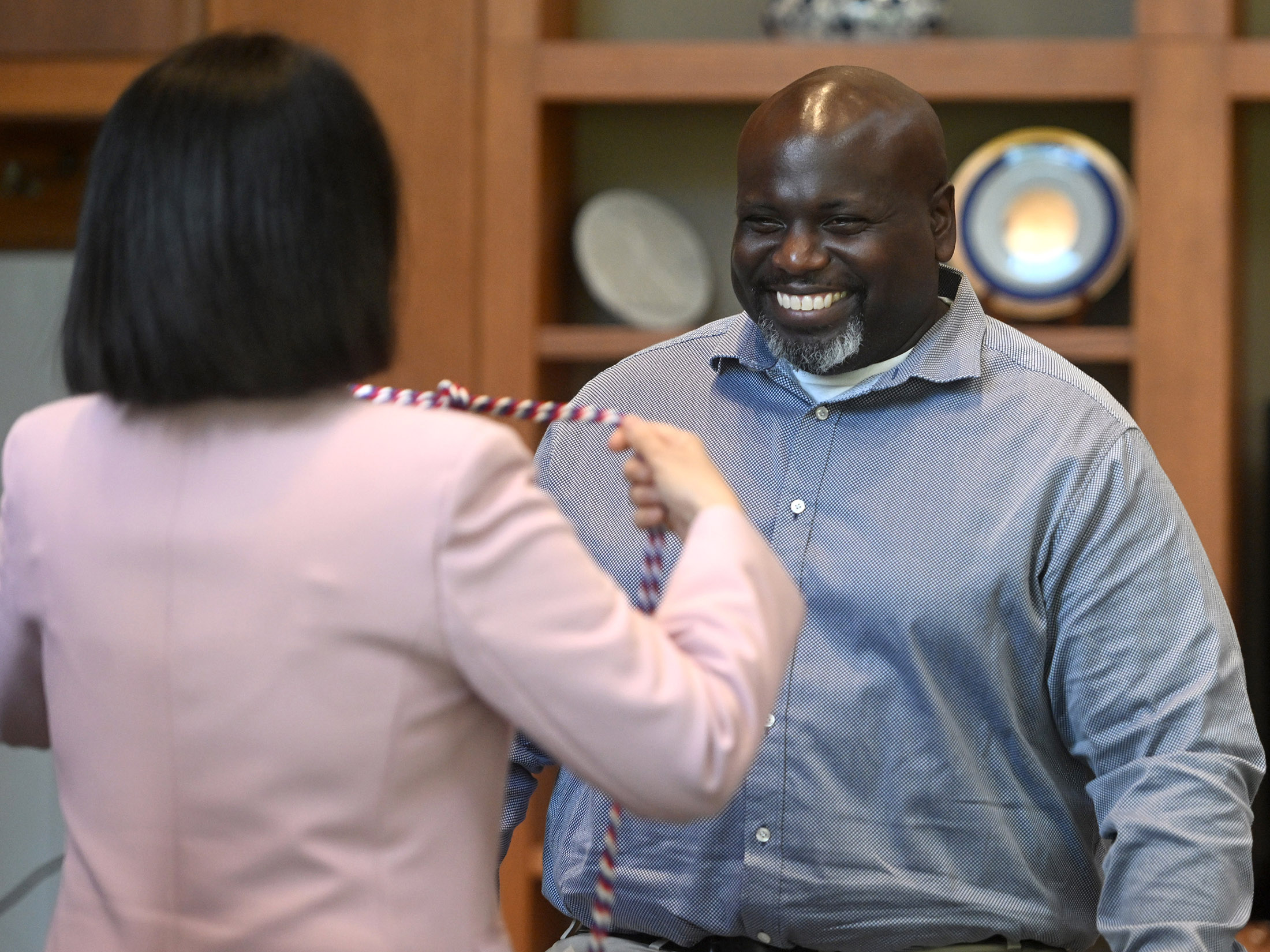 A man receives red, white, and blue honor cords from a woman.