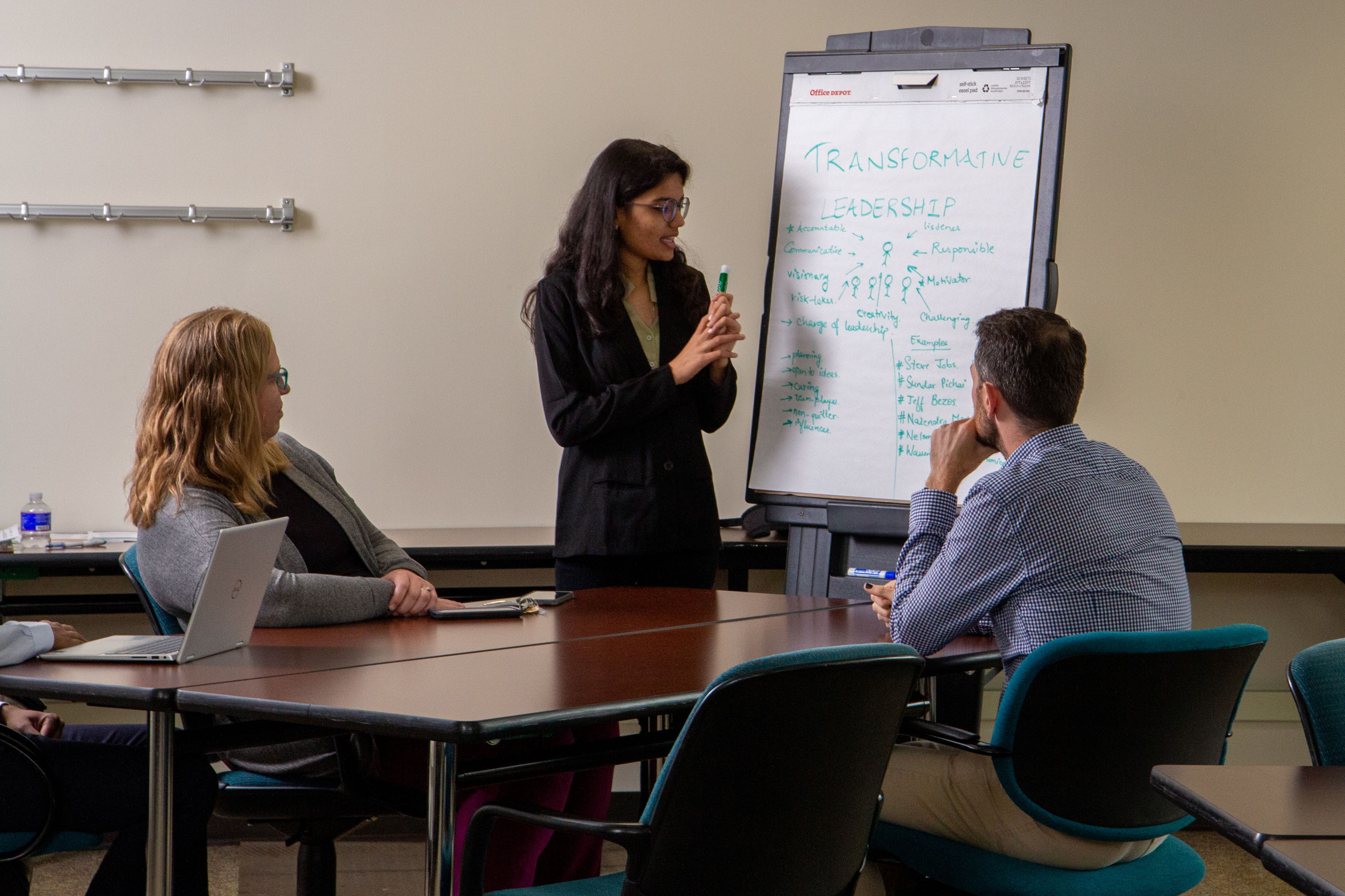 A businesswoman presents about transformative leadership to two colleagues