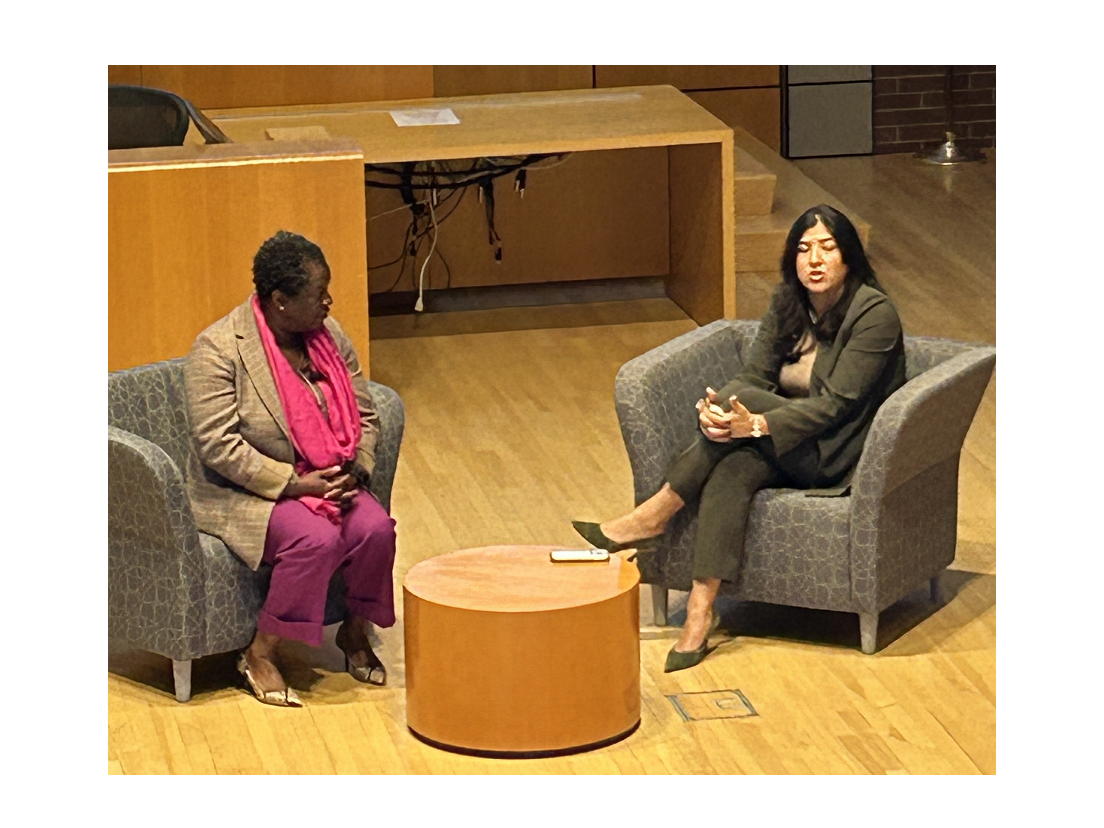 Two women speaking at an event, sitting across from each other in chairs