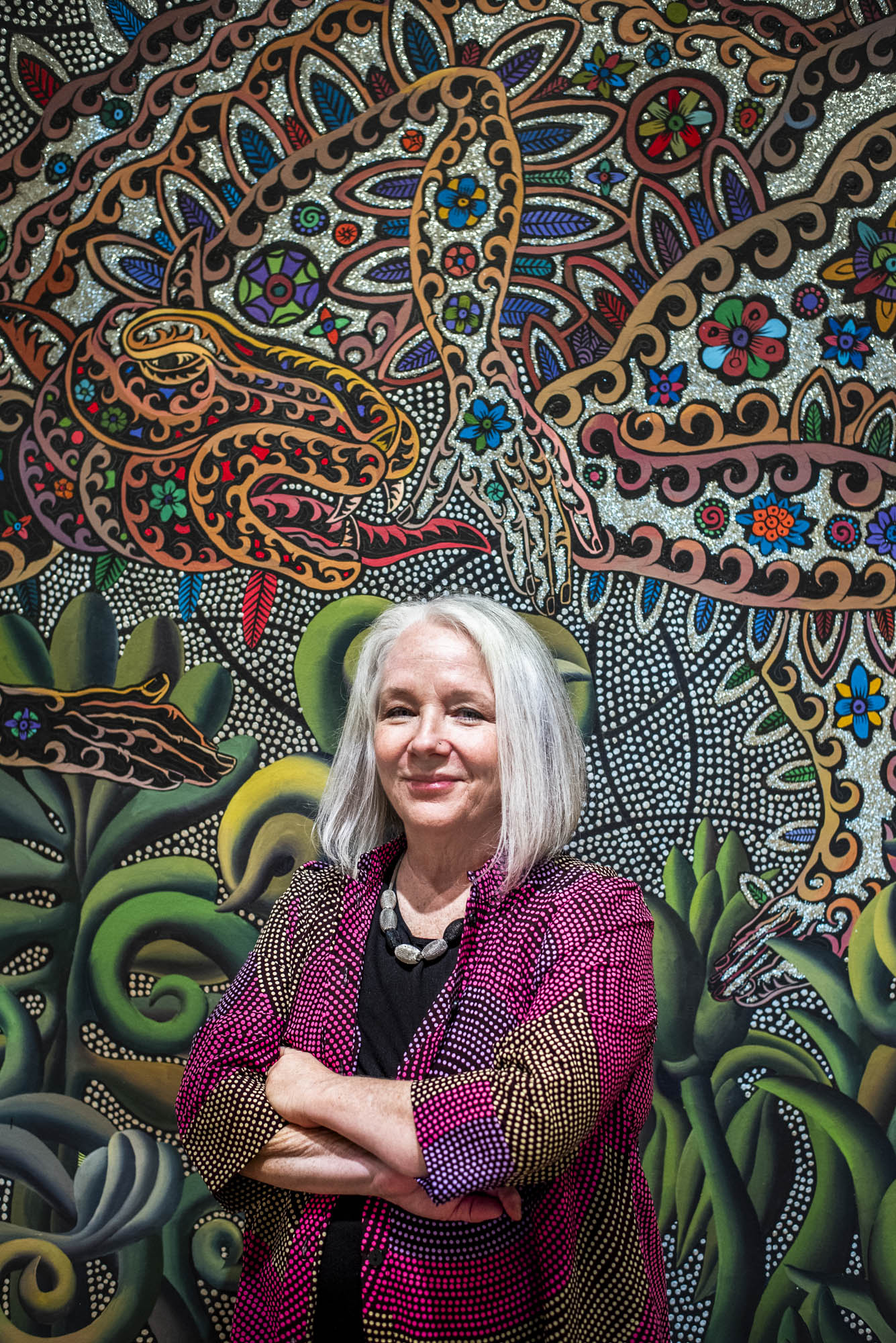 Women with chin-length gray hair in front of multicolored wall