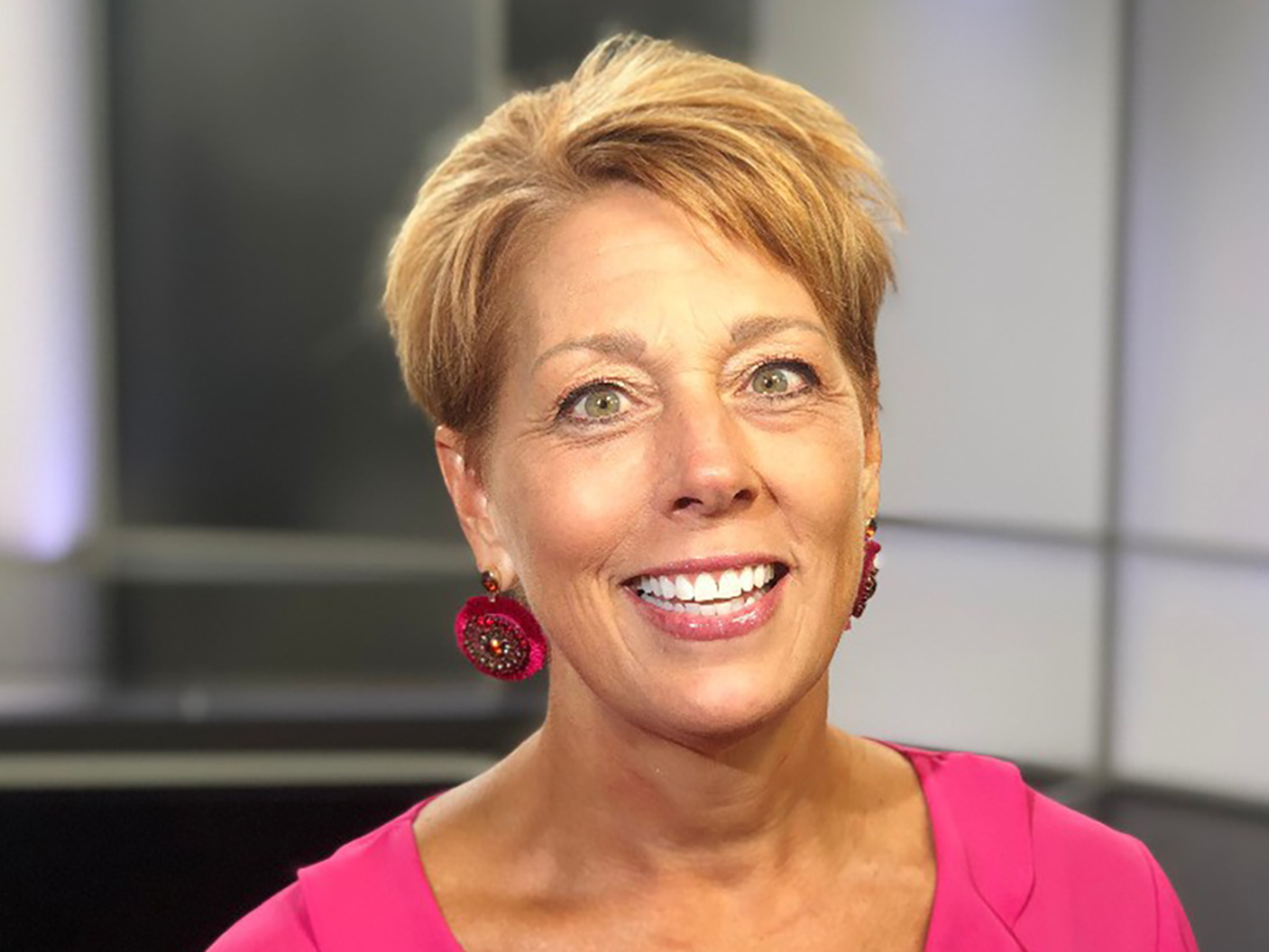 Smiling woman with short blonde hair and a pink top