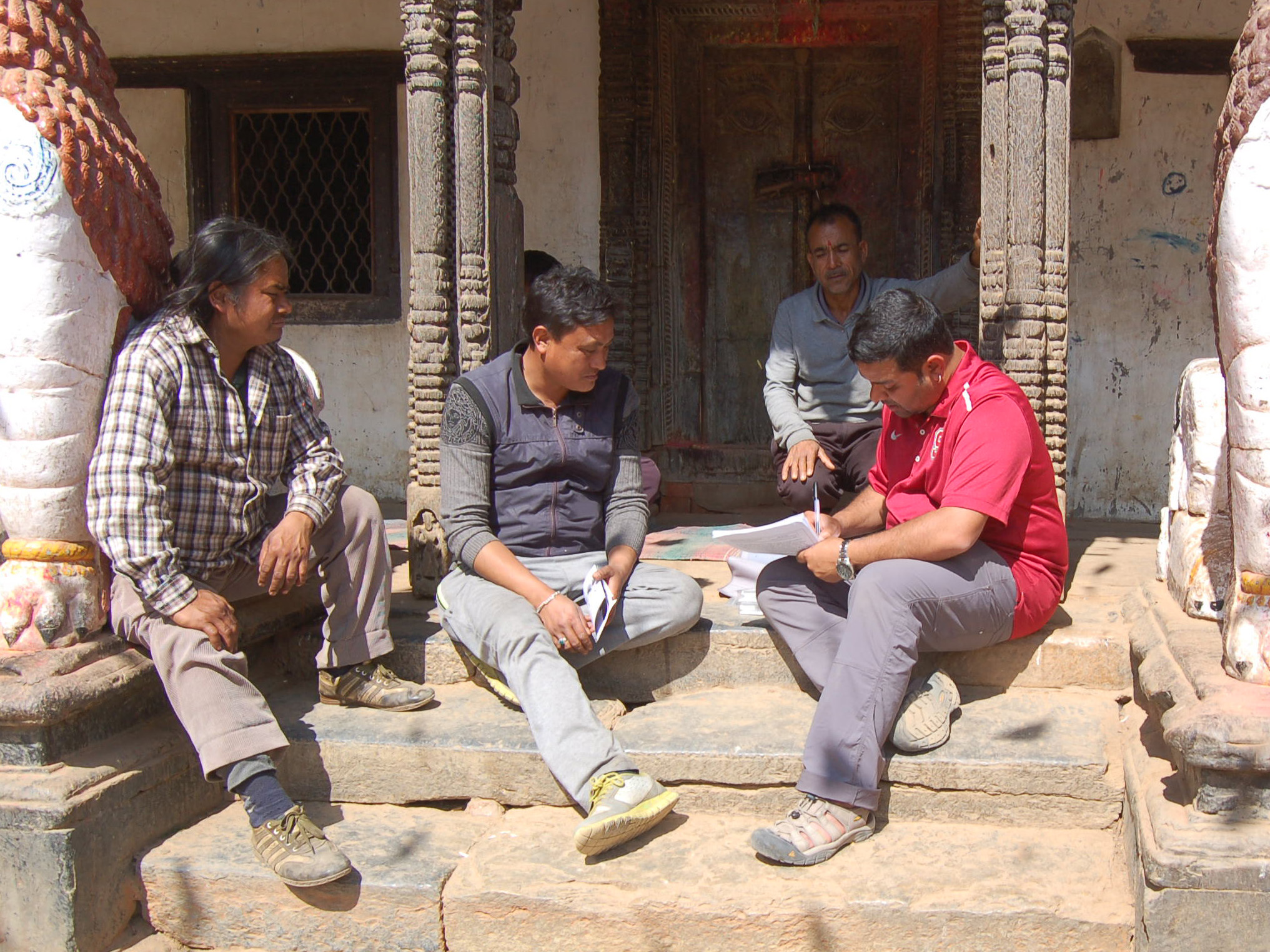 group of men sit on steps with a researcher