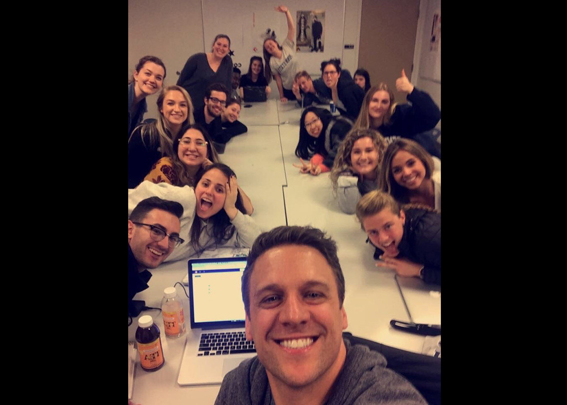 Ryan Russell taking a selfie with his students around a long table. 