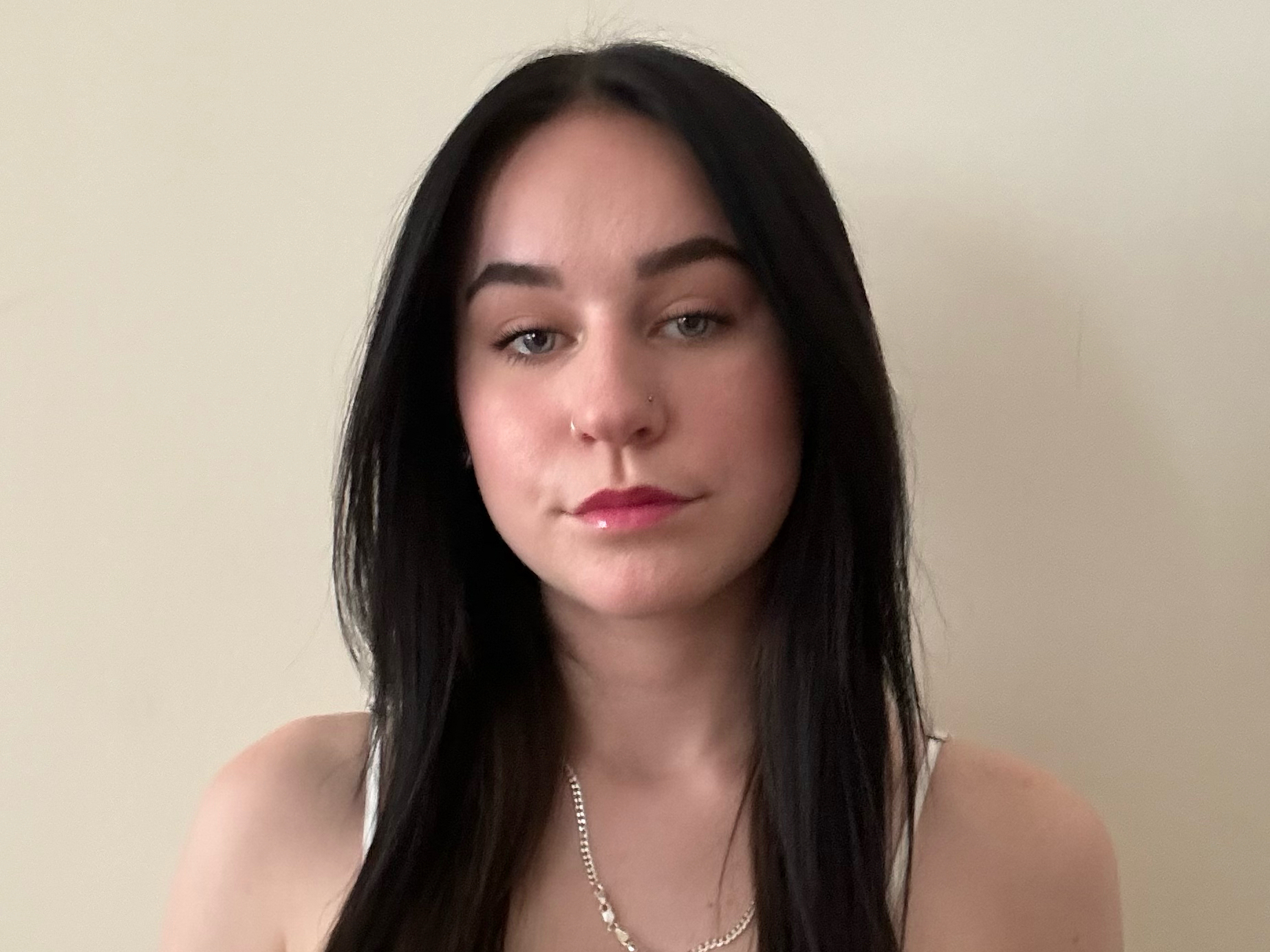 Sarah Stein poses for a headshot in front of an ivory wall.