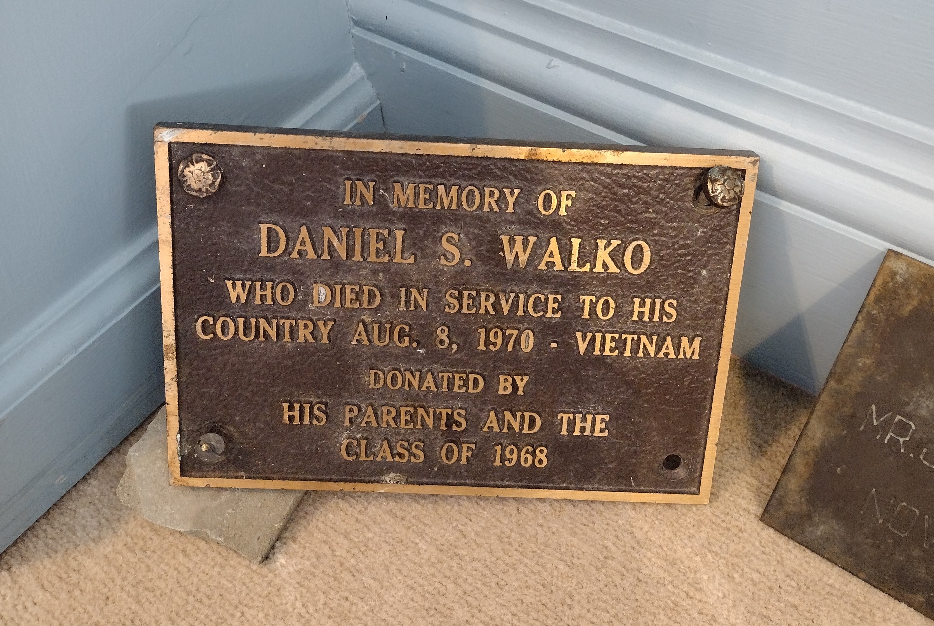 A plaque in memory of fallen servicemember Daniel S. Walko rests on the ground.