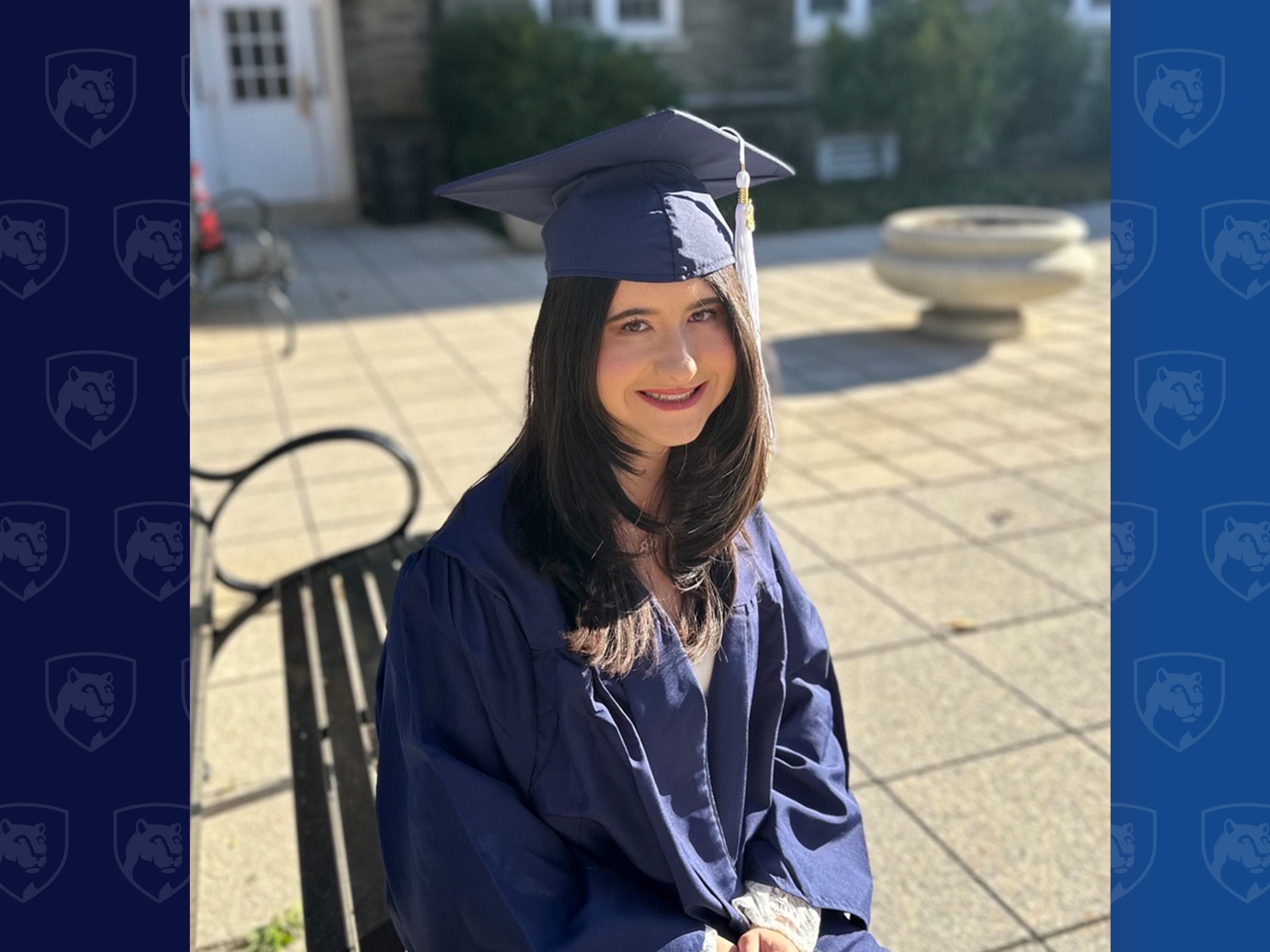 Student in cap and gown sitting outside