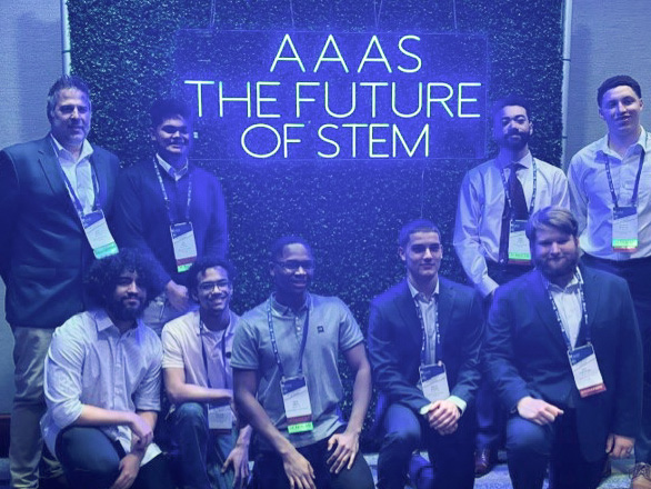 Group of students in front of neon sign reading "AAAS The Future of Science"