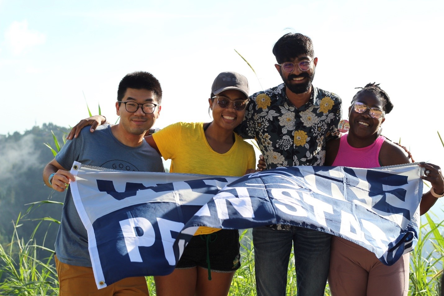 Four students with a Penn State flag in a field