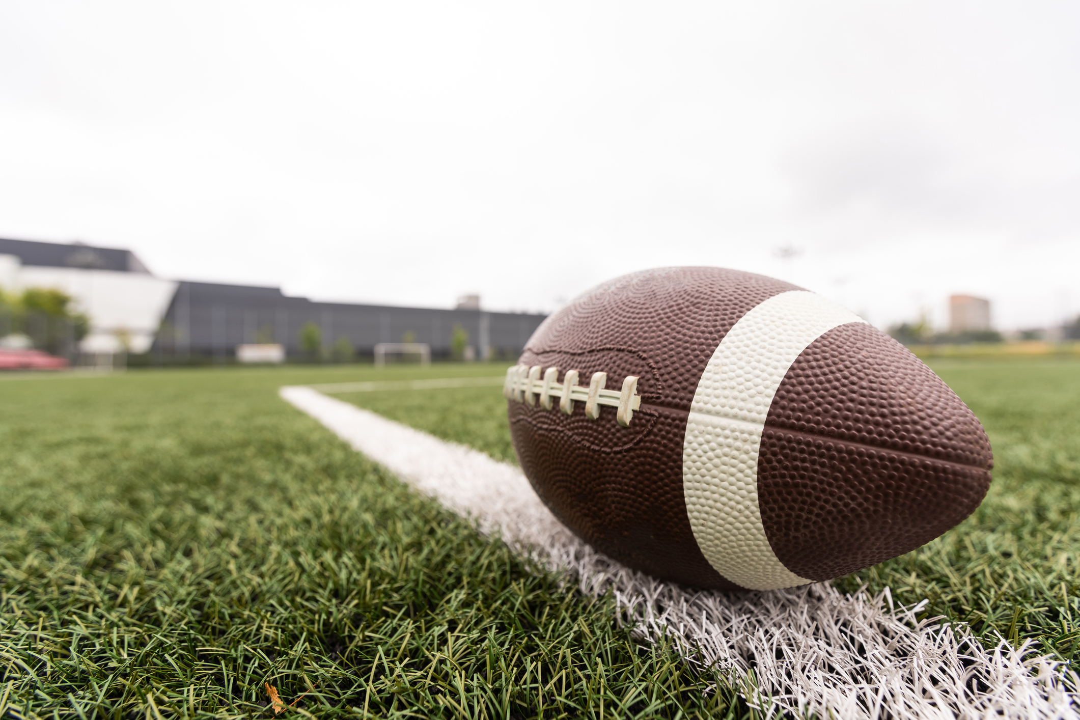 a football in the foreground rests on a football field