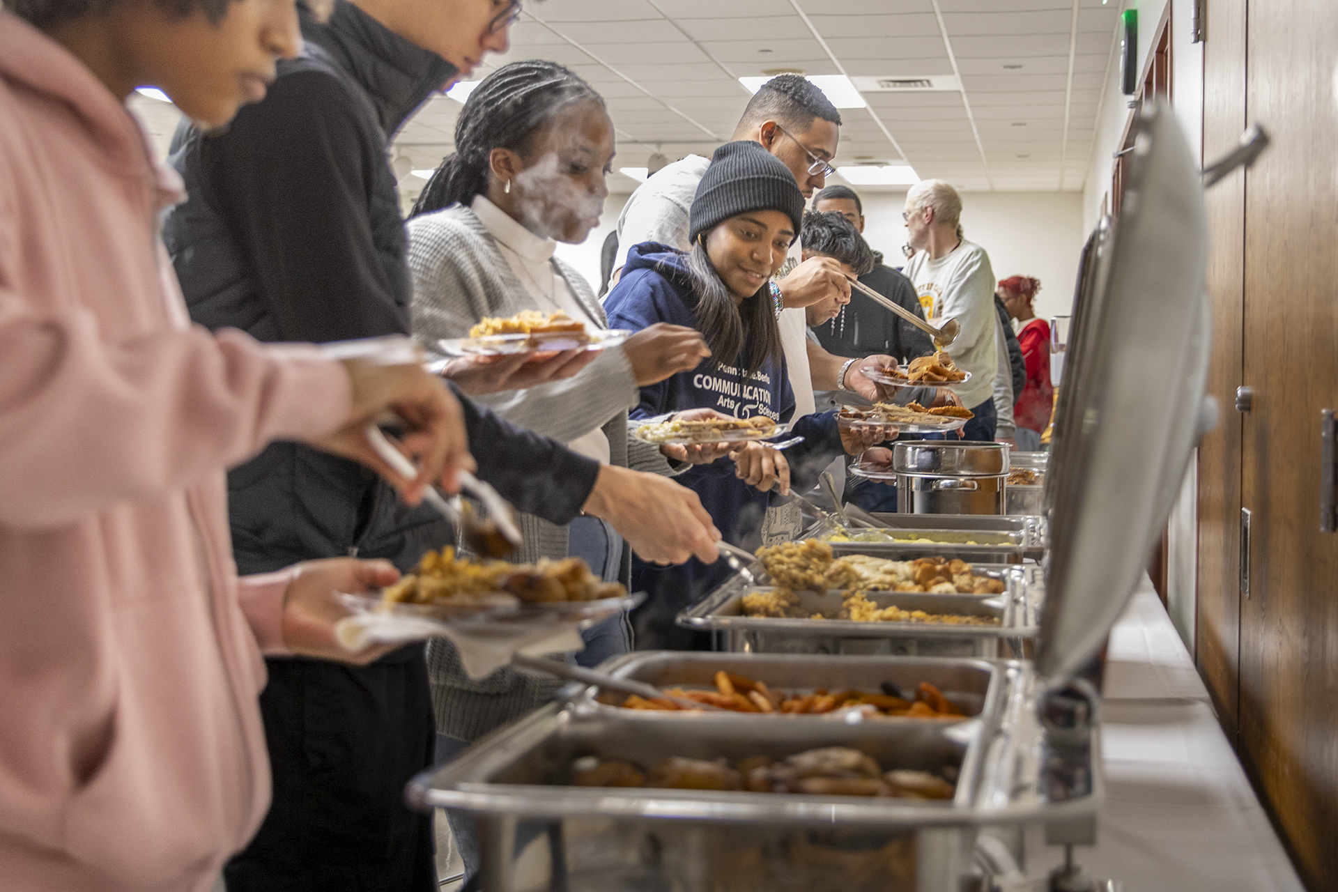 Students serve themselves food from chafing dishes.