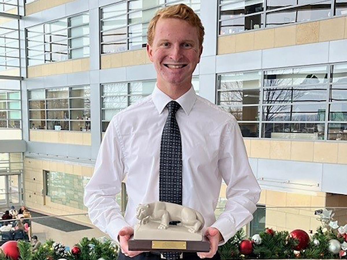 A photo of Justin Stough holding a replica of the Lion Shrine.